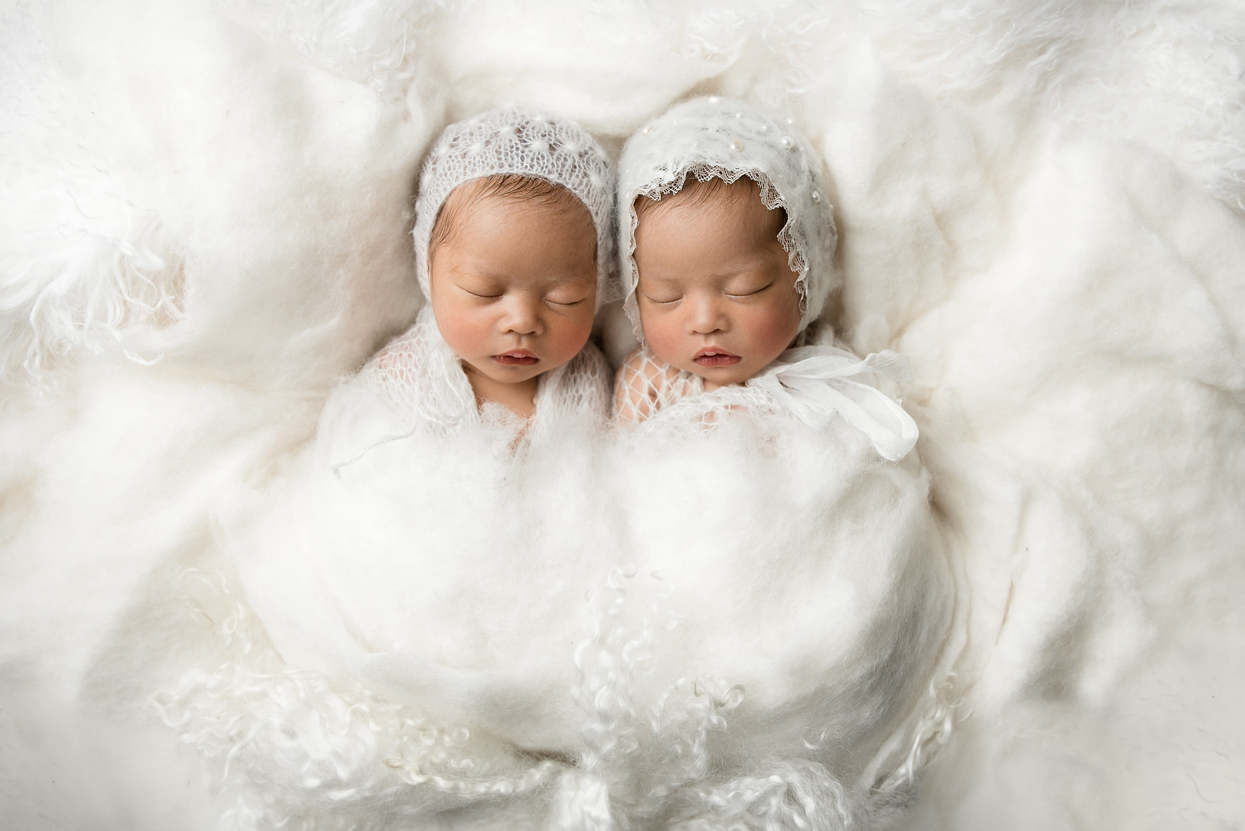 asian twins wrapped and snuggled together at junebug photography studio in manhattan, kansas