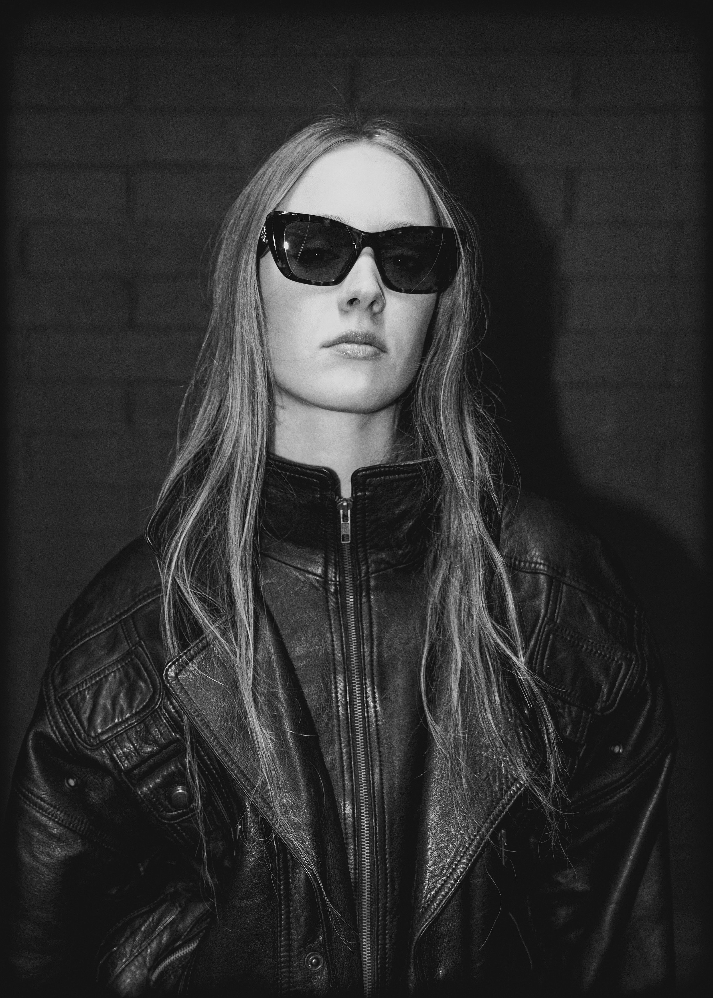 Black and white portrait fashion model Aubrey wearing a vintage leather jacket, styling by Julian Castaneda and posing for an editorial fashion photo