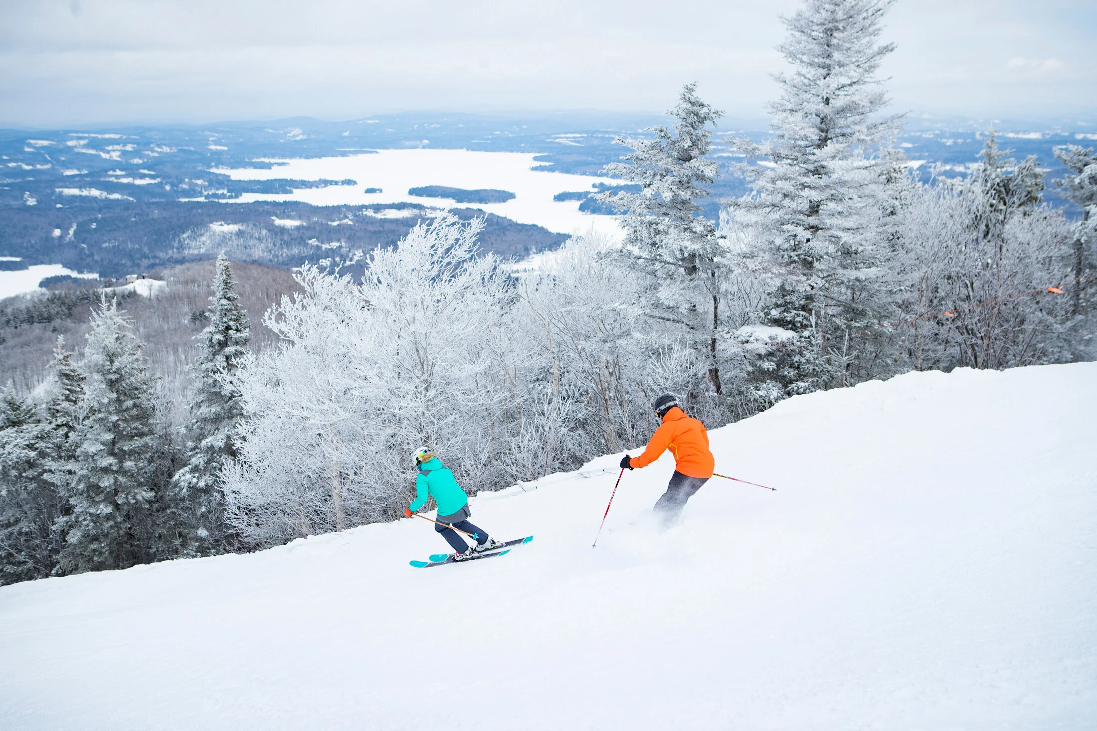 Photo courtesy of Vail ResortsA couple of skiers cruise down a trail with a beautiful view of the valley in front of them.