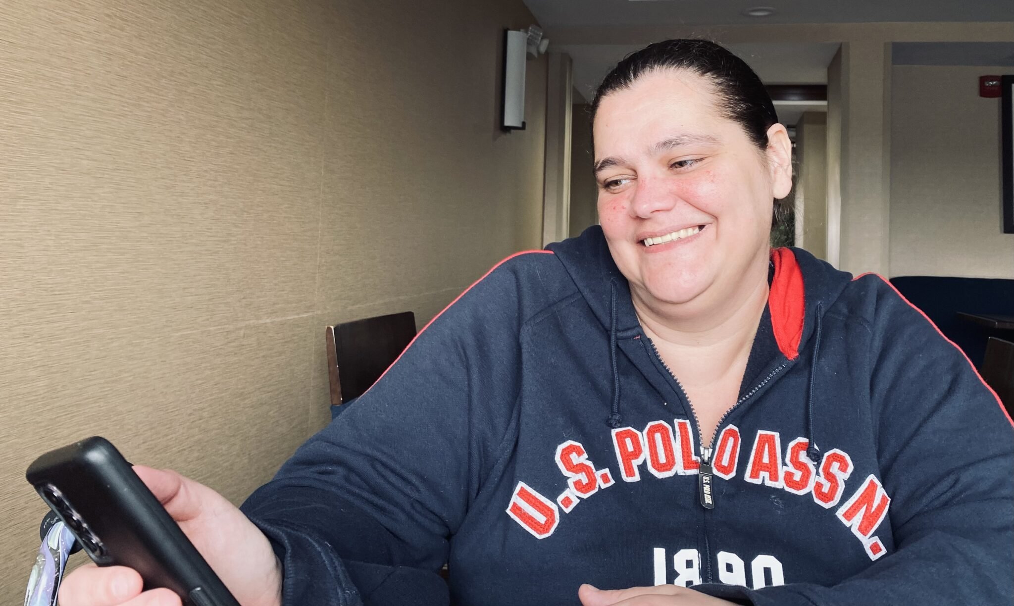  Nicole Eastman smiles while looking at a picture of her teenage daughters on her phone. She’s been living at the Comfort Inn for seven months and has had no luck finding an apartment. Photo/Pat Grossmith  