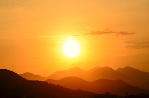 Sun setting in orange sky over mountain range