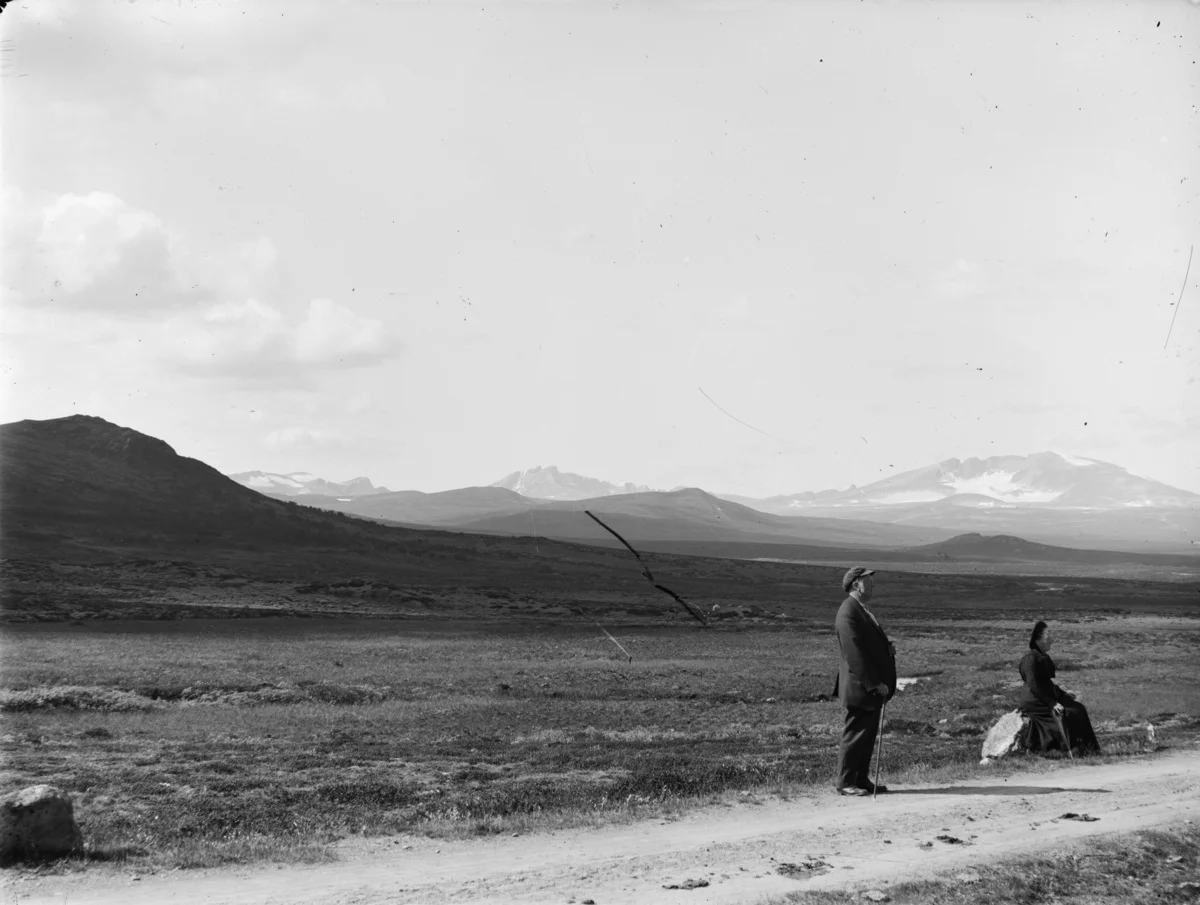 Om infrastrukturen og bygninger forandrer seg, står fjellene støtt. Snøhetta og Svånåtind fotografert fra vegen cirka 1890-1910.