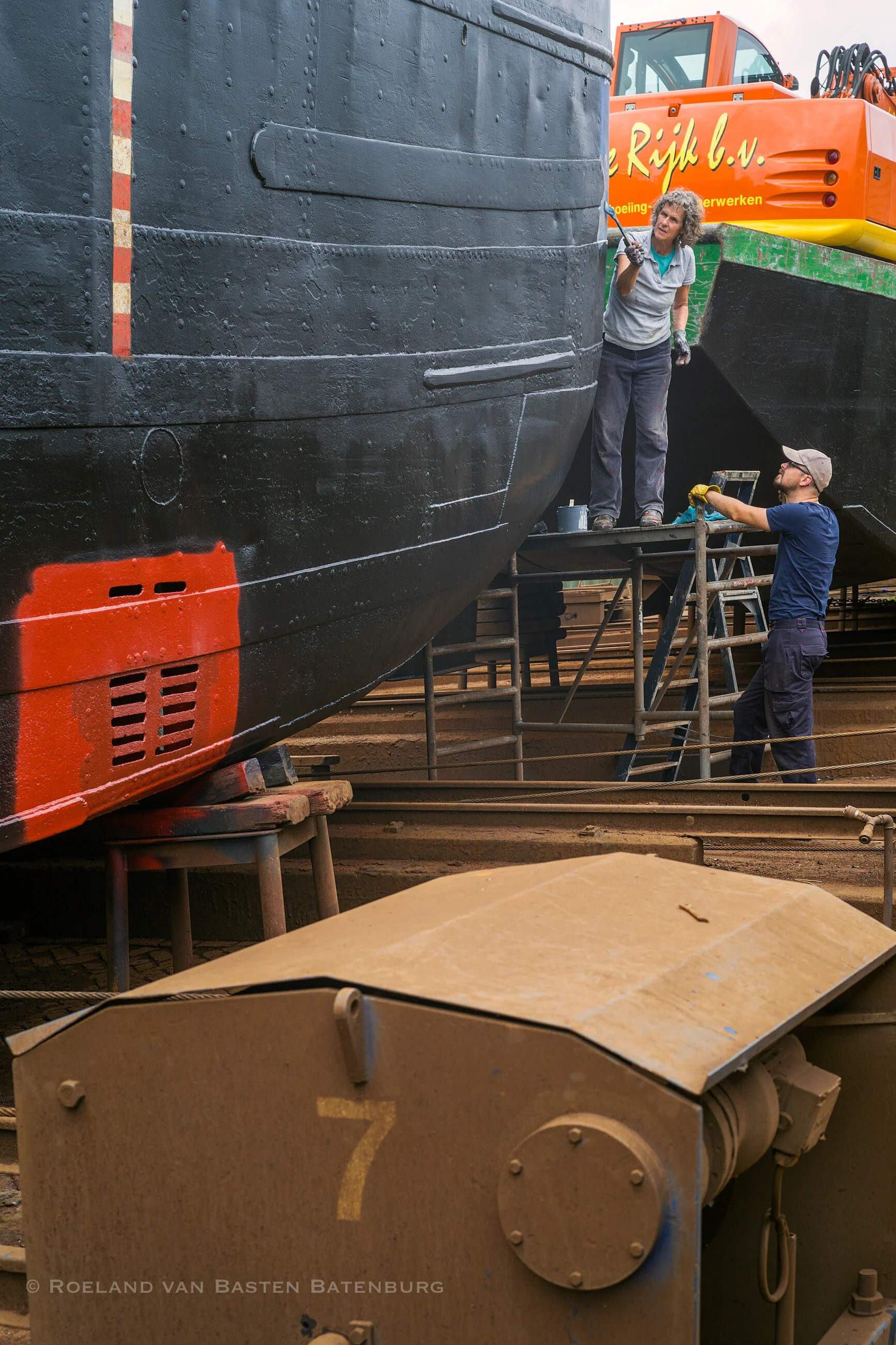 De nieuwe laag teervervanger zit er intussen op, meerdere lagen tot aan de waterlijn (met leeg schip), daarboven een enkele van weer een andere samenstelling. Degelijk vakwerk. Het oranje-rode stuk is antifouling op de waterinlaat van de beunkoeler, die vervangen is