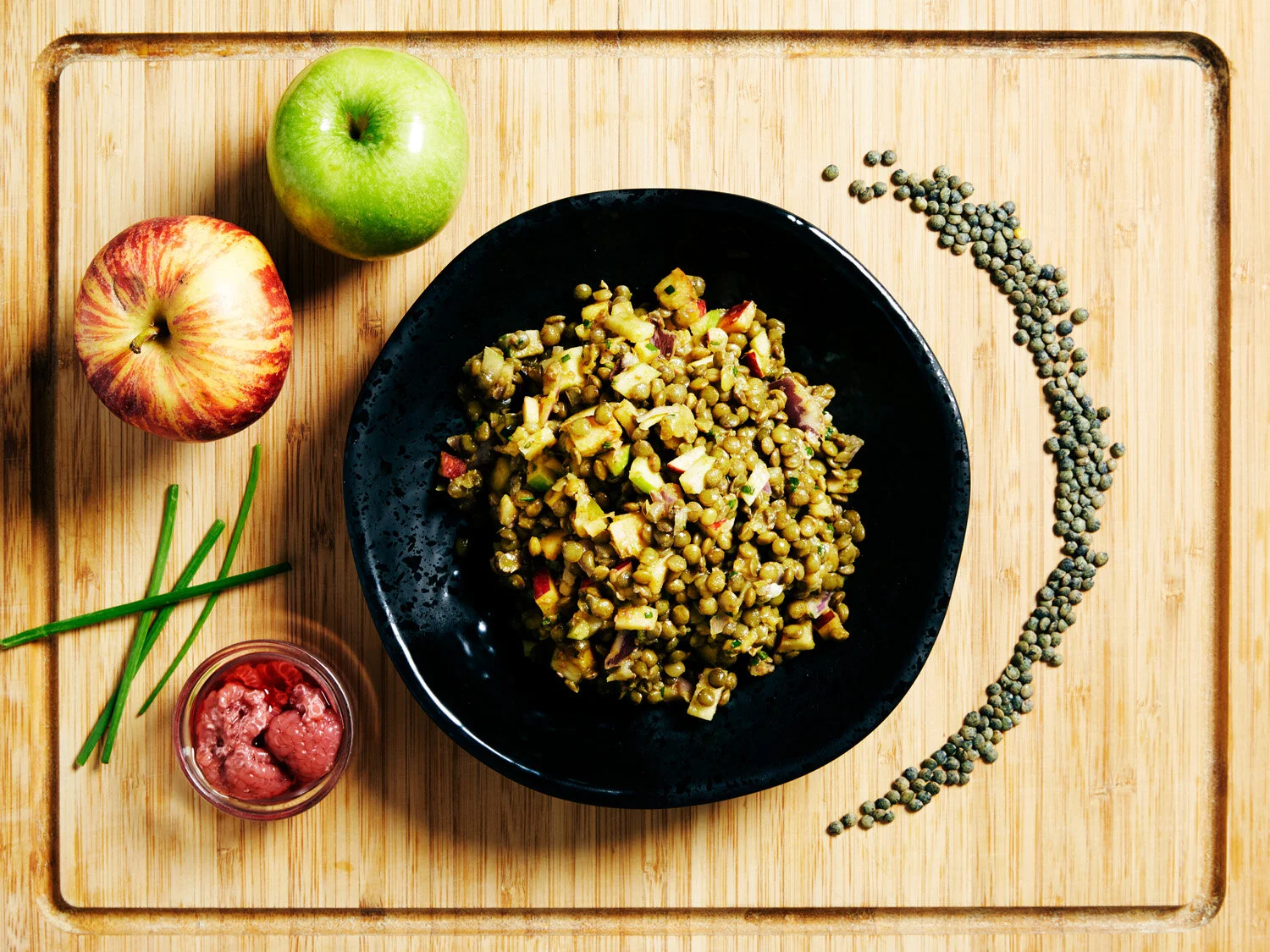 Salad Du Puy served on a wooden board with apples and raspberries