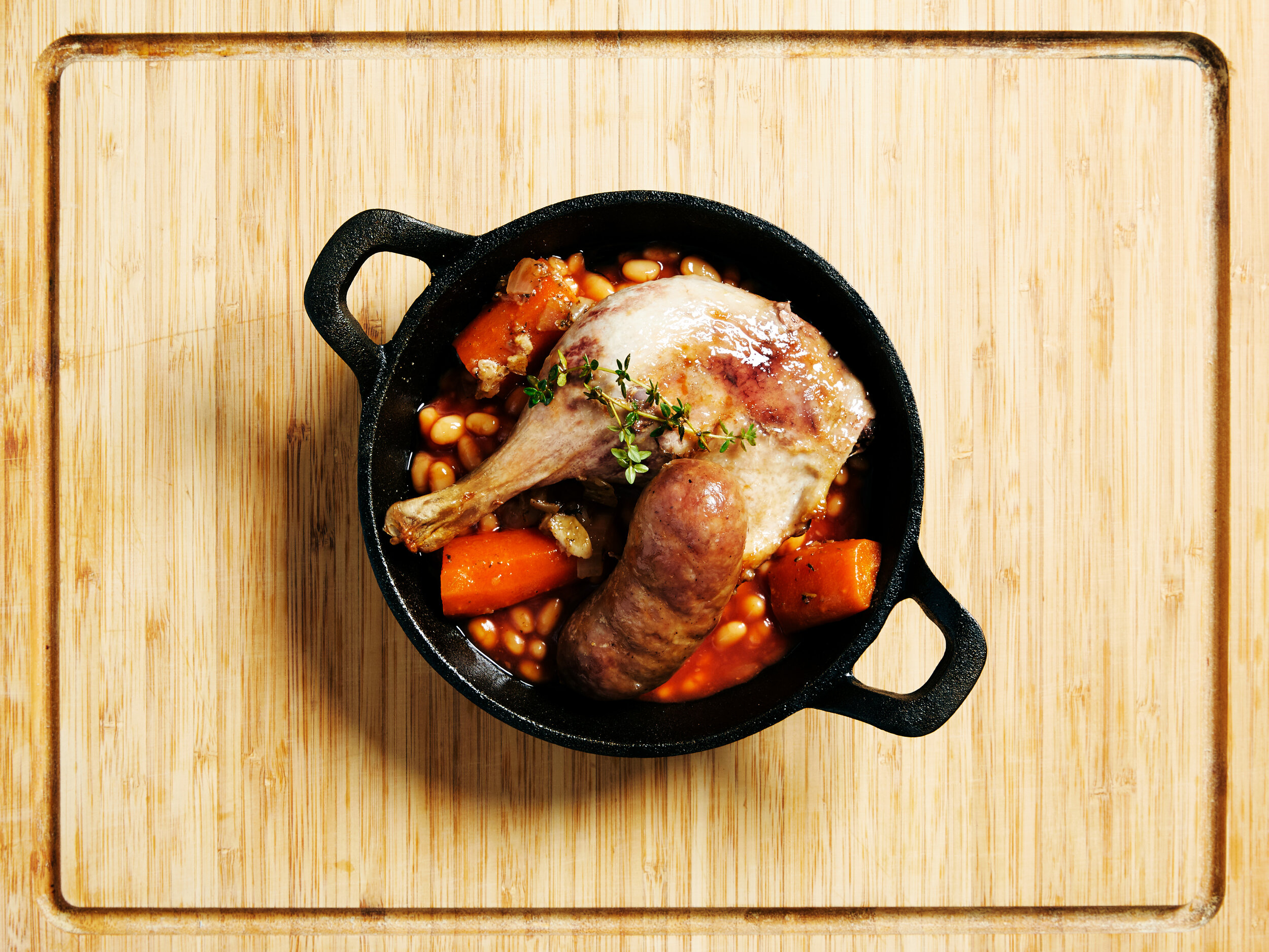 Cassoulet Royale served in a black metal pot on a wooden chopping board (Copy)