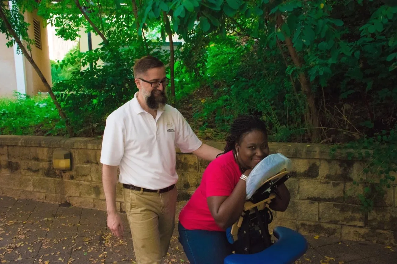 Michael Patrick having completed an outdoor chair massage. Woman client is relaxed and happy.