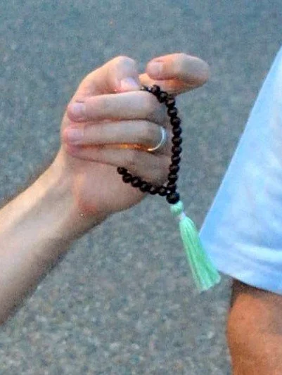 holding wrist mala with fingers and thumb