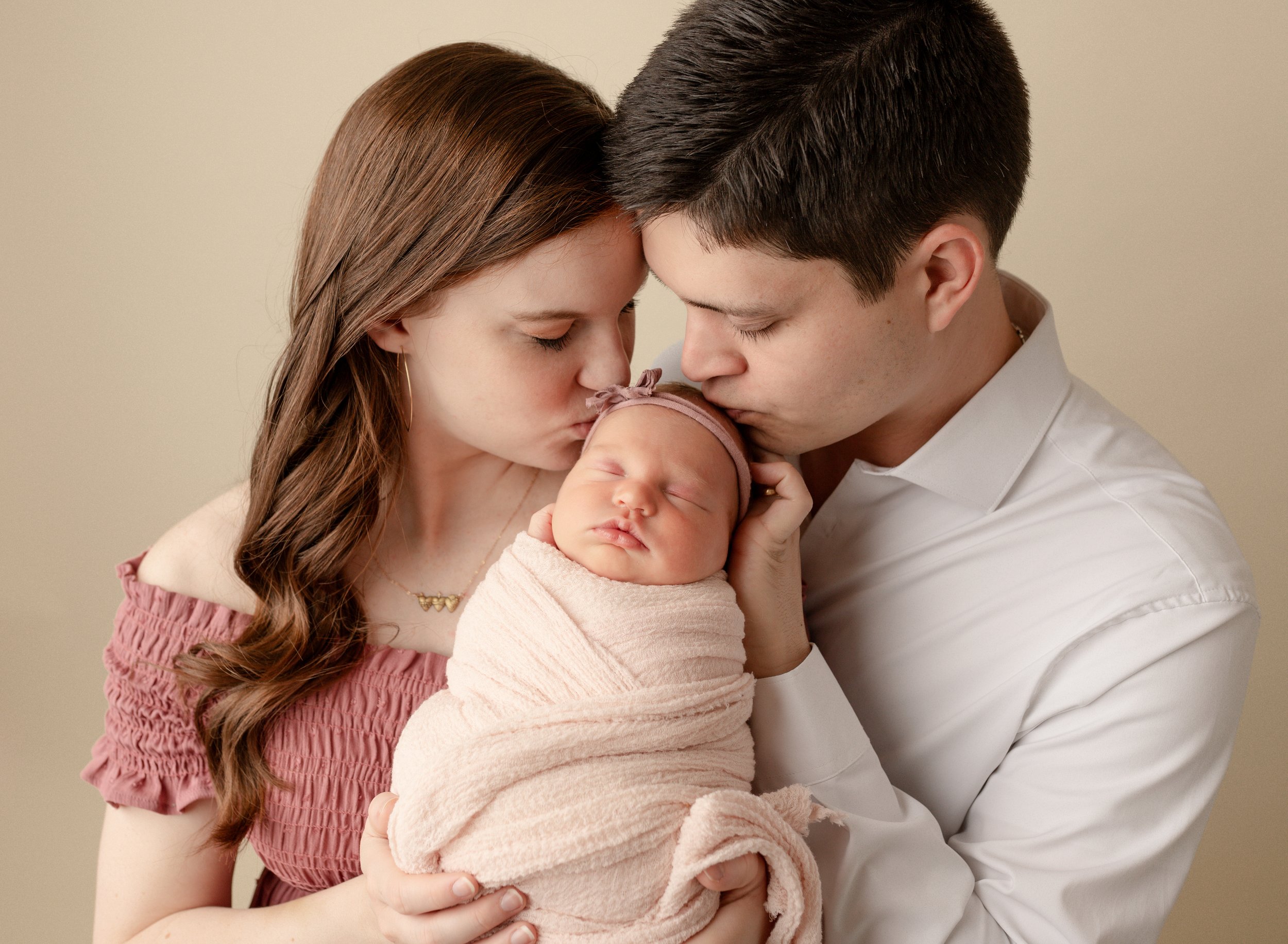 parents-kissing-newborn-daughter.jpg