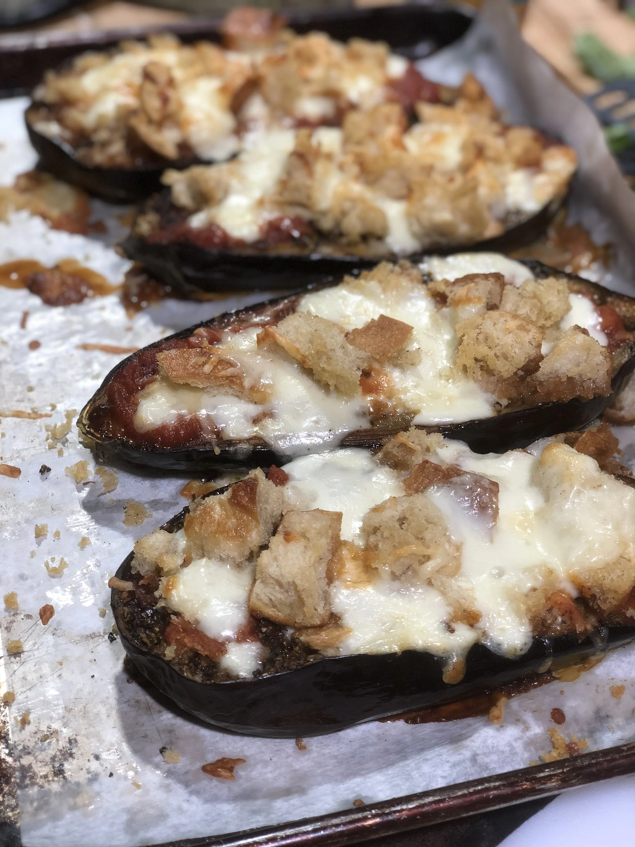 Unfussy Eggplant Parmesan from Skillet and Sheet Pans: Summertime Suppers Cooking Class at Red Stick Spice Co. in Baton Rouge. Unfussy Eggplant Parmesan Serves 4 Ingredients ¼ cup Basil Extra Virgin Olive Oil 1 tsp salt 2 tsp Tuscan Blend 2 medium globe eggplant 1 cup D’agostino marinara sauce or a jarred marinara 1 cup bread cubes ½ cup fresh mozzarella cheese 4 Tbl grated parmesan cheese Directions Pre-heat oven to 400 degrees Cut the eggplant in half lengthwise, now cut a diagonal l crosshatch pattern in each about ½ inch deep. ¾ -inch diamonds. Line a rimmed sheet pan with parchment. Place the eggplant halves on top, cut side facing up. Drizzle with Basil Extra Virgin Olive Oil and sprinkle with the blend and salt. Rub the oil and seasoning into the eggplant with your hands. Roast for about 30 minutes or until tender. During the last couple of minutes, add the bread cubes to the sheet pan to toast a little. Pull from the oven and raise the temperature to 475 degrees. Mix the mozzarella and the parmesan cheese in a small bowl to combine. Top each eggplant with a few Tbl of marinara sauce spreading evenly with a spoon. Now top each with a quarter of the cheese. Then each with bread cubes. Finish with remaining cheese Put back in oven for 5 minutes or until cheese is bubbly and browned. Let cool before serving.