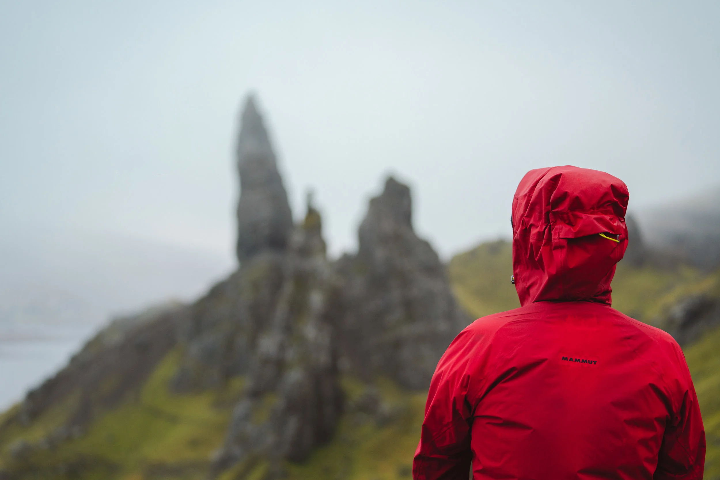 Man looking to Old Man of Storr with a Mammut red jacket