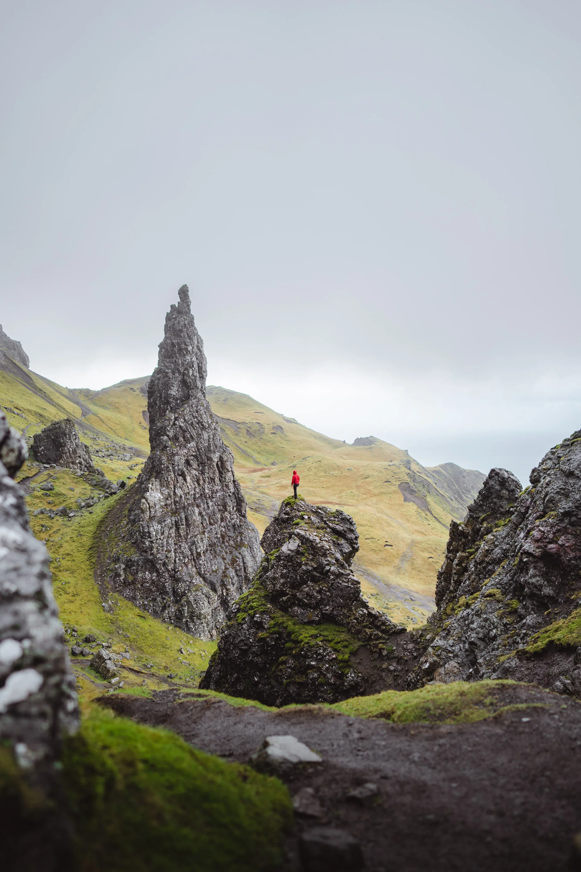 Man with a Mammut red jacket climbing in Old Man of Storr, Scotland