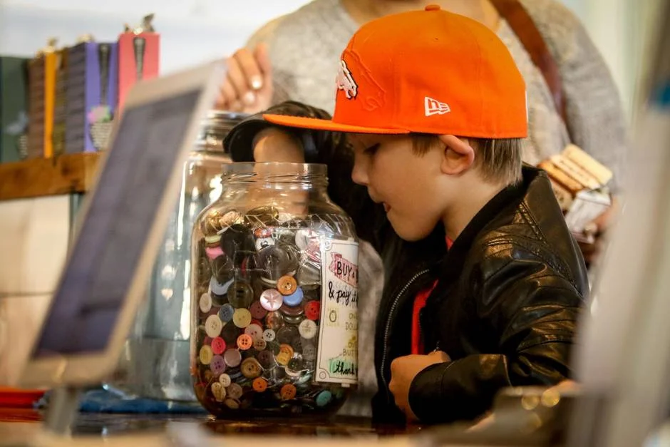 Ryder Fasulo, 7, reaches into the Button Bank at 541 Eatery and Exchange to buy a button for a dollar which will then turn into currency (valued at a dollar) that can be used by someone in need, towards a purchase of a coffee or a meal. Five buttons can be used per day per person.