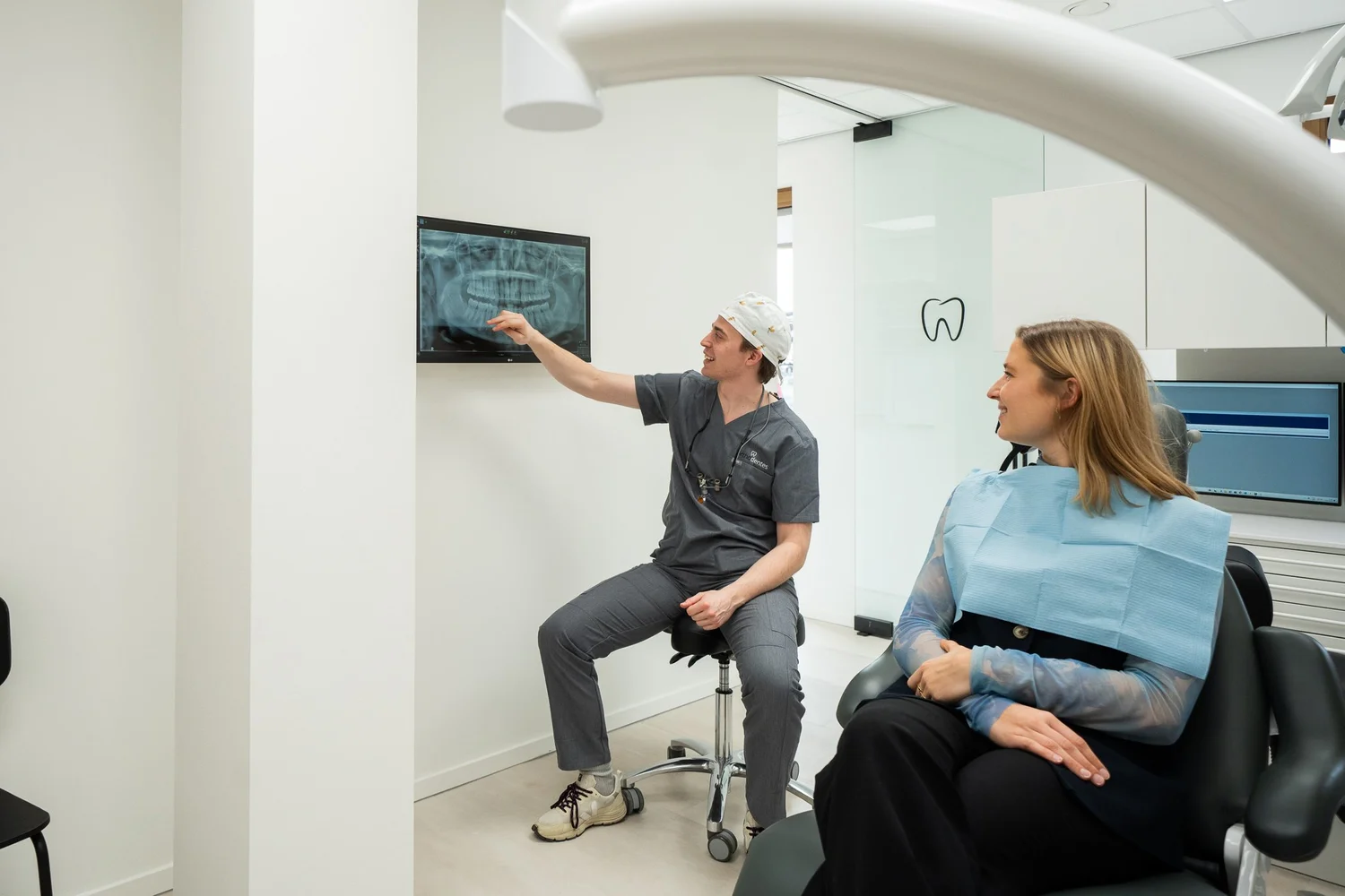Een tandarts bespreekt een röntgenfoto met een patiënt bij Orthodentes in Wilrijk.