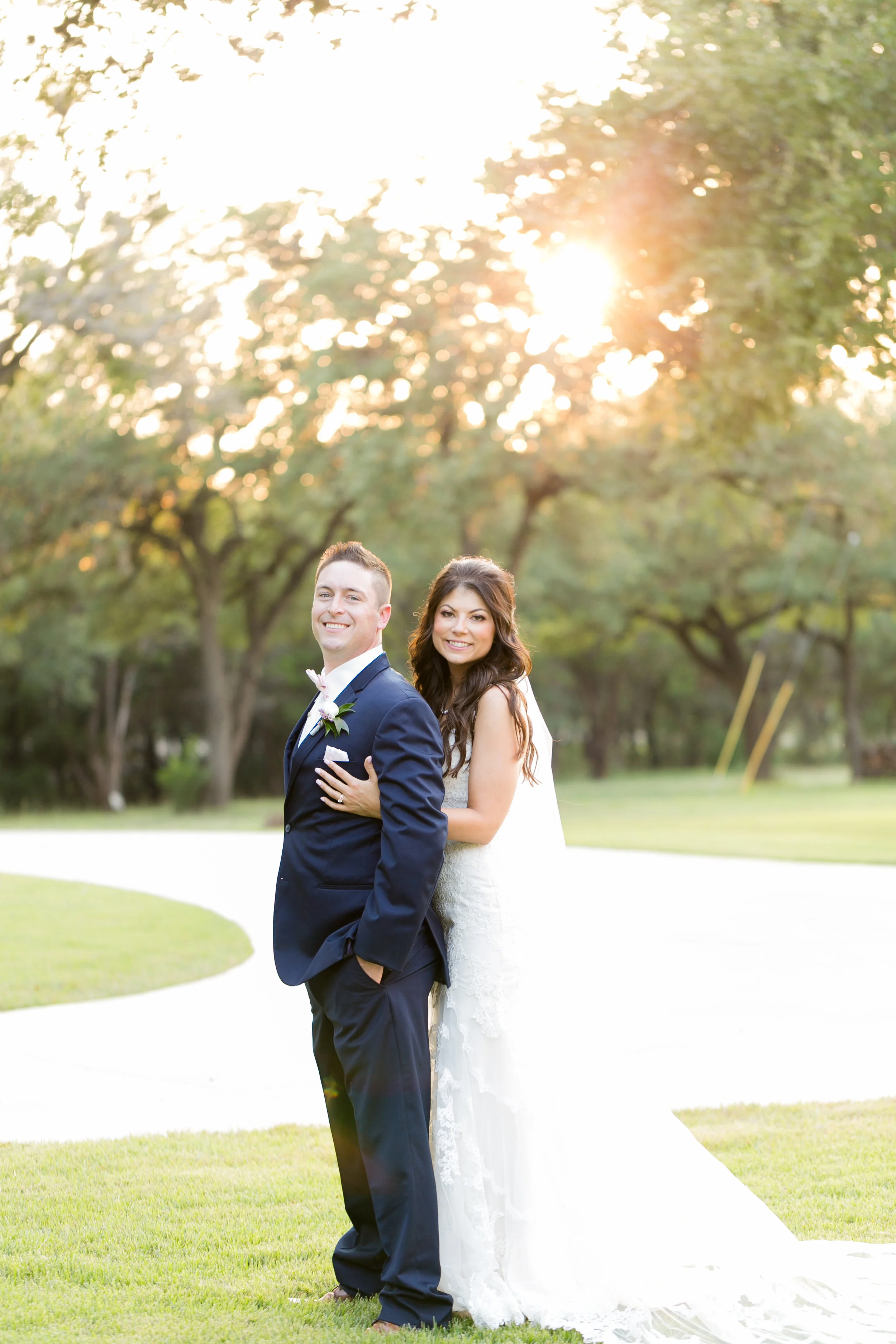 Bride and groom smile outside at sunset