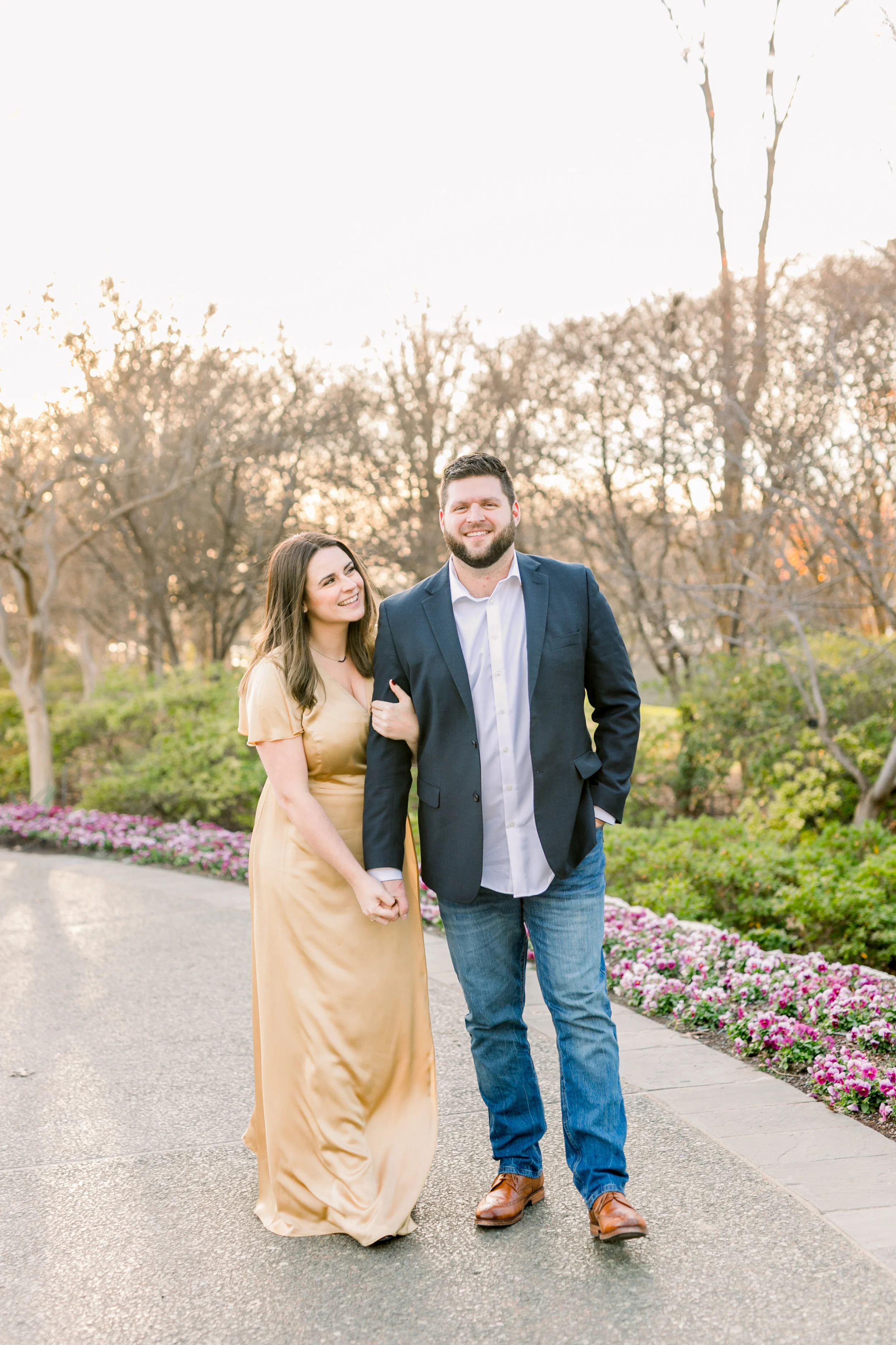 Couple outside at sunset in park walking by flowers