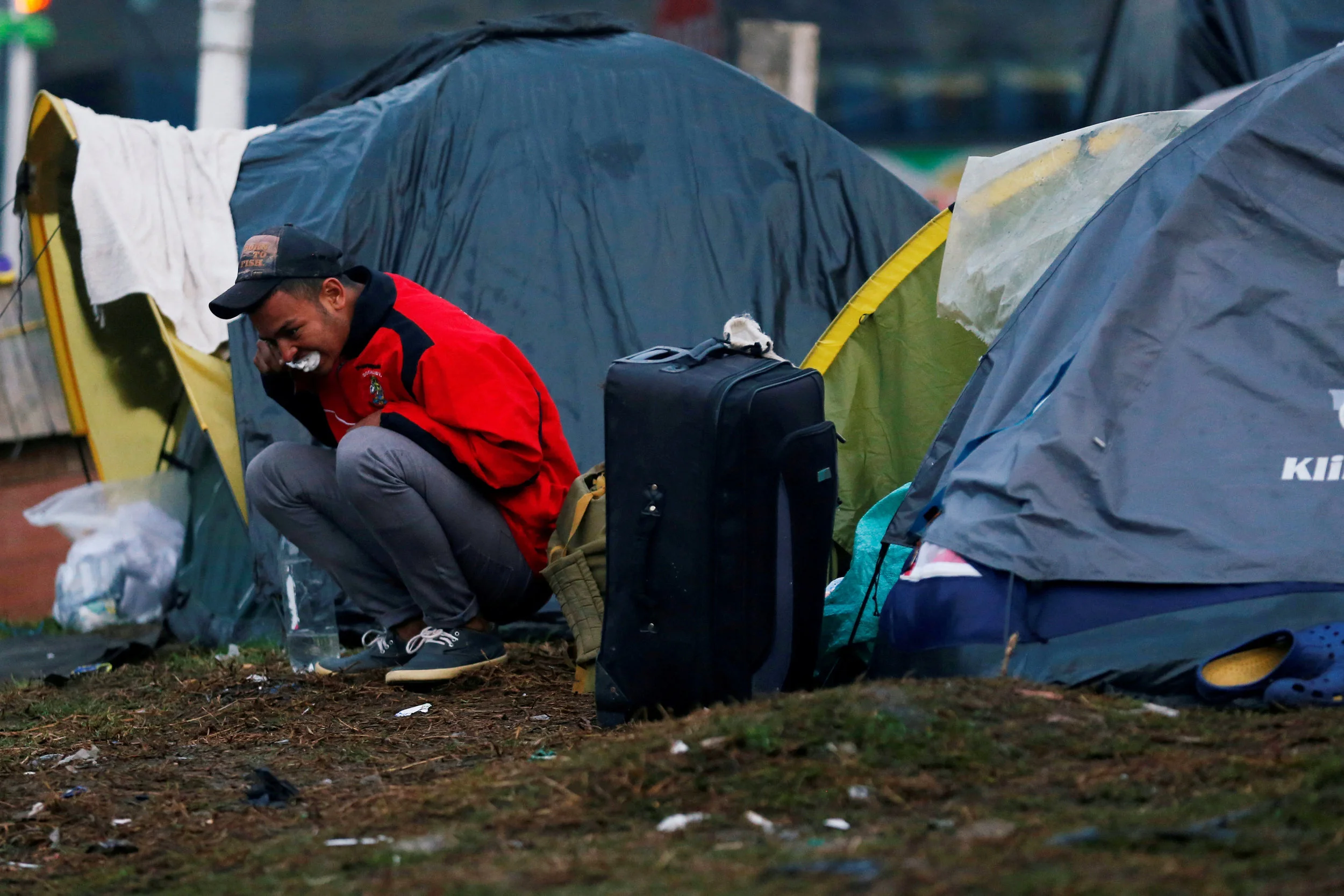 A Venezuelan migrant brushes his teeth outside his tent at a makeshift camp Nov. 26 in Bogota, Colombia. [Photo: NS photo/Luisa Gonzalez, Reuters]