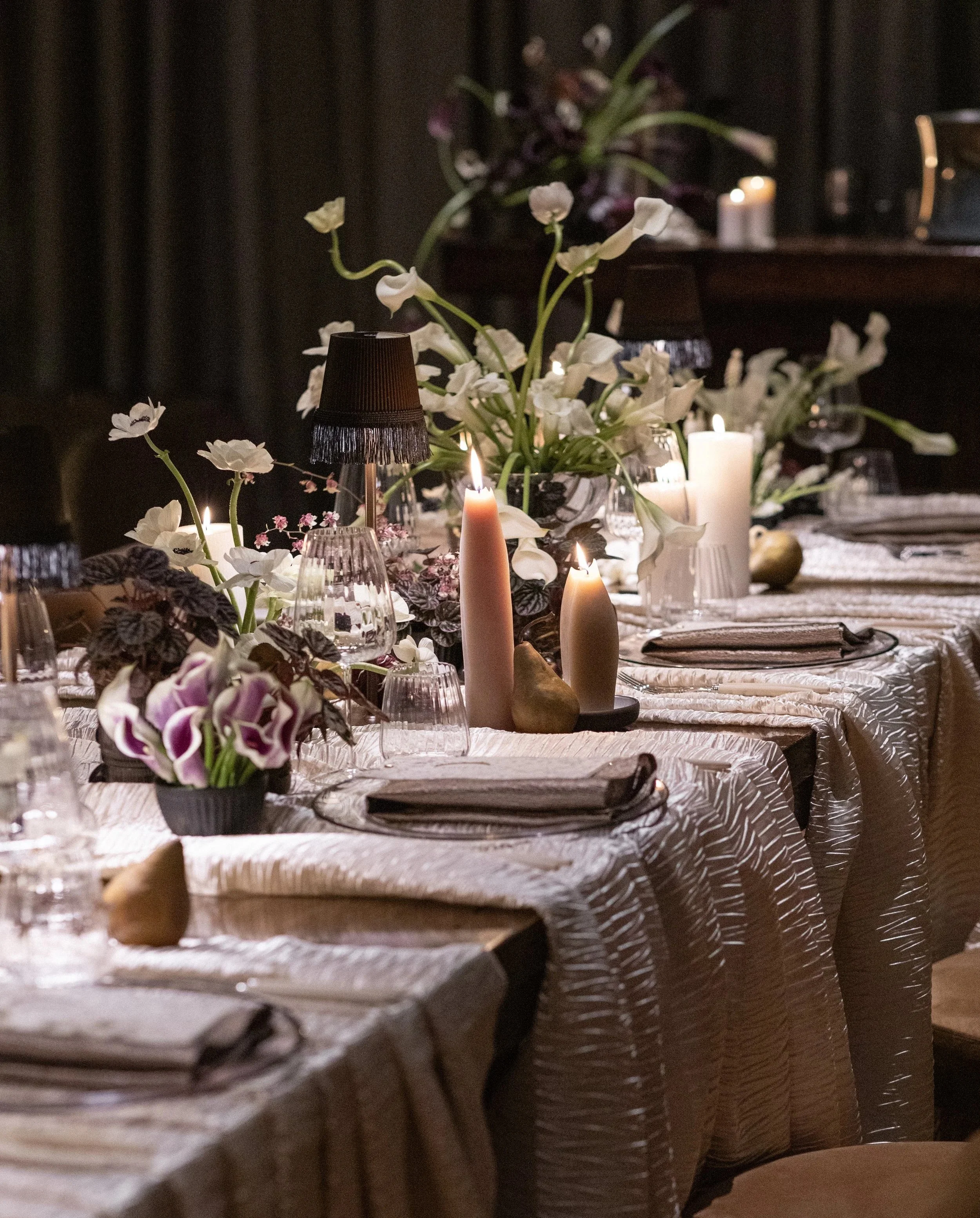 Sophisticated, elevated table featuring luxury white flowers, candles, and tableware, set for a wedding or corporate event dinner.