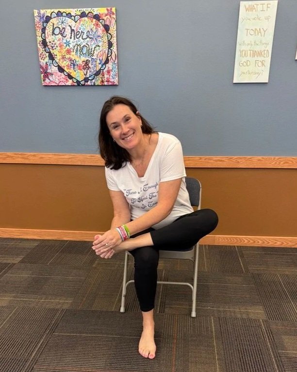 Krista demonstrating a supported chair-yoga pose using a chair.