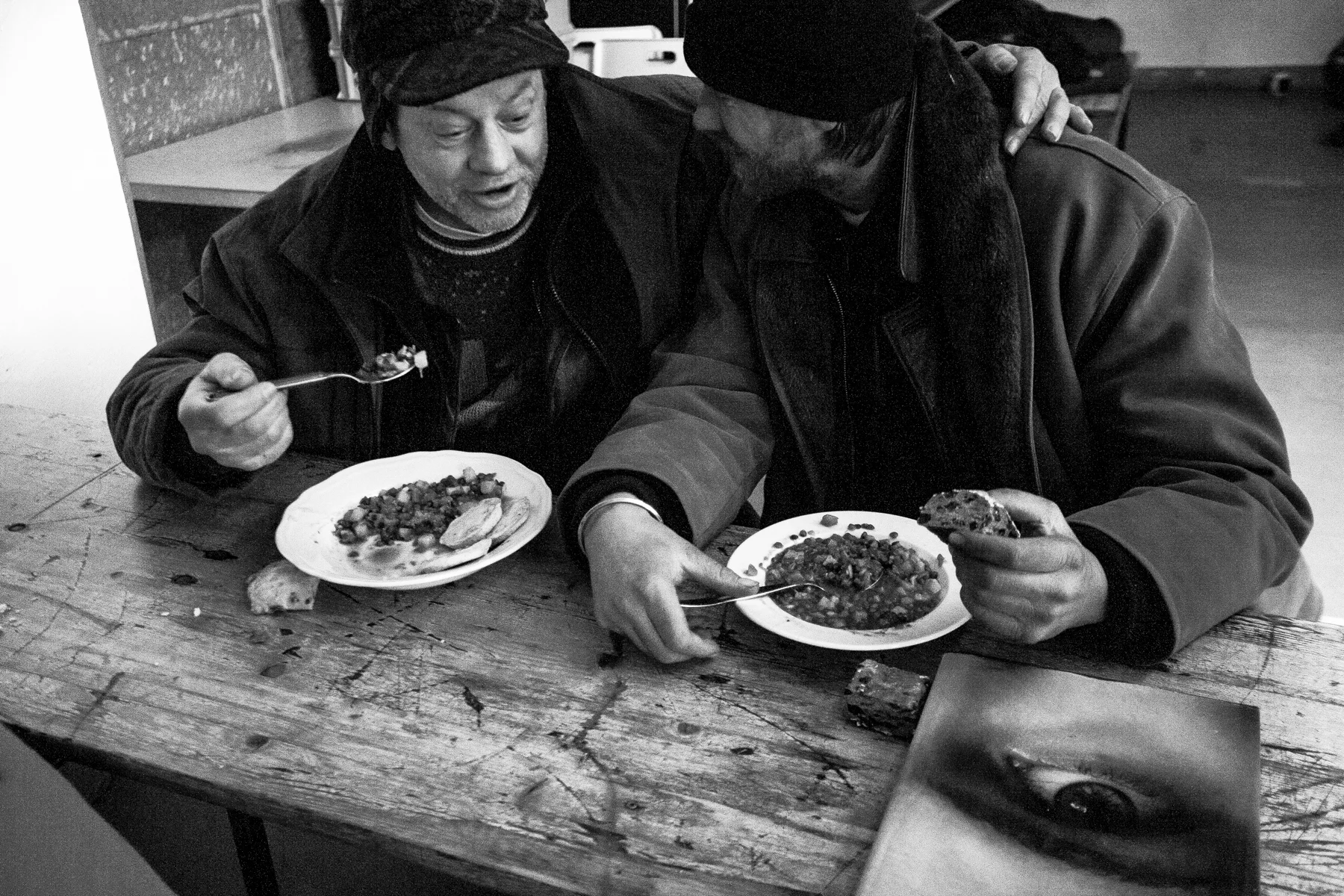 Two friends eating. There was a shelf on the side with few books people could borrow and read. One of the guys stood up and went by himself to pick that book. I didn’t say a thing, but when I was aiming I loved that eye looking at us like a mirror.