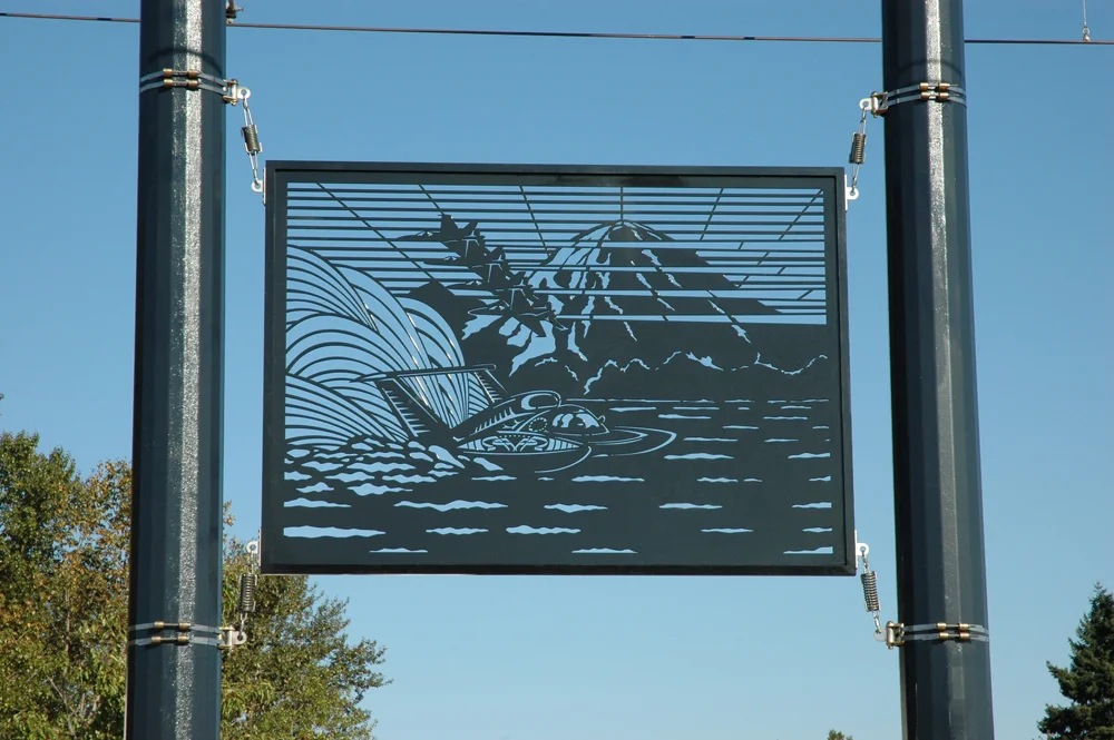 Reiquam's panel entitled Seafair, depicts Seattle's annual Seafair Festival featuring hydroplane races on Lake Washington and the Navy Blue Angels flying against a backdrop of Mount Rainier.