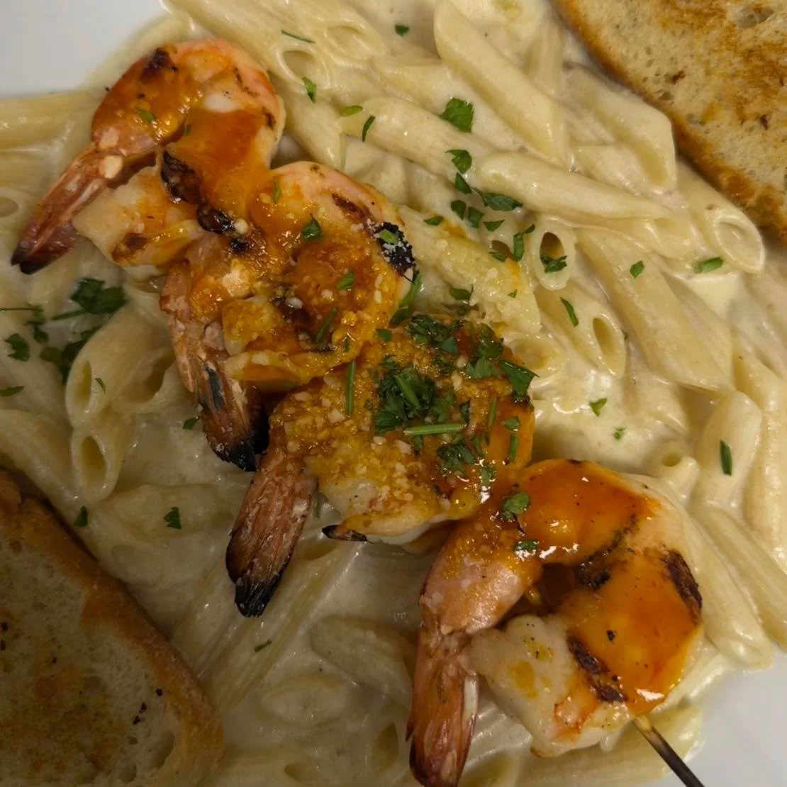 At The Ranch House , we keep it simple: creamy pasta, smoky BBQ shrimp, and a little grilled bread love on the side. 🍤🔥🍝

This plate&rsquo;s got everything &mdash; buttery bbq glazed shrimp fresh off the grill, rich creamy penne, and that home-mad