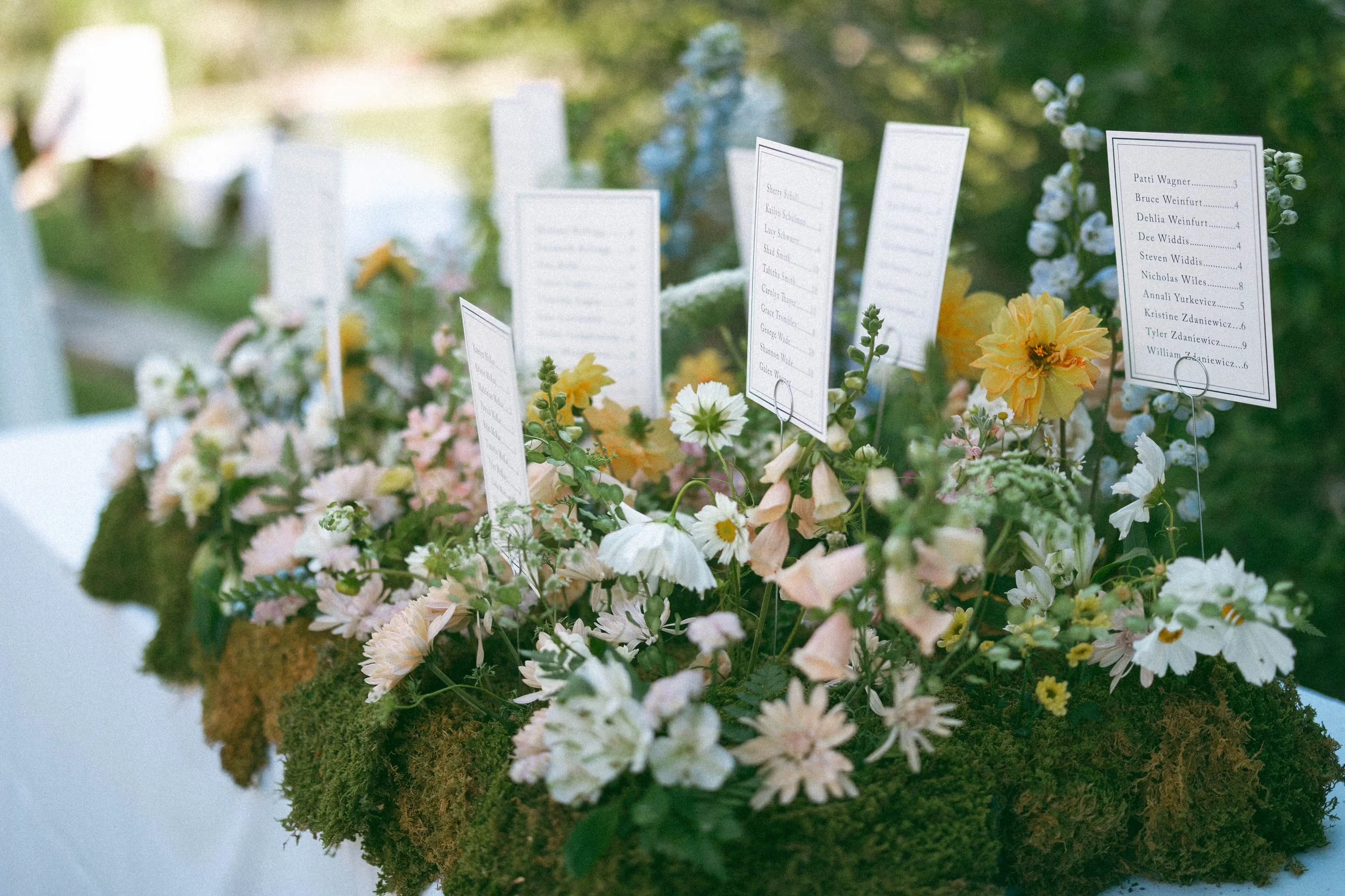 Mossy floral seating chart. Moss covered in pastel florals and cards for guest to find their seats.