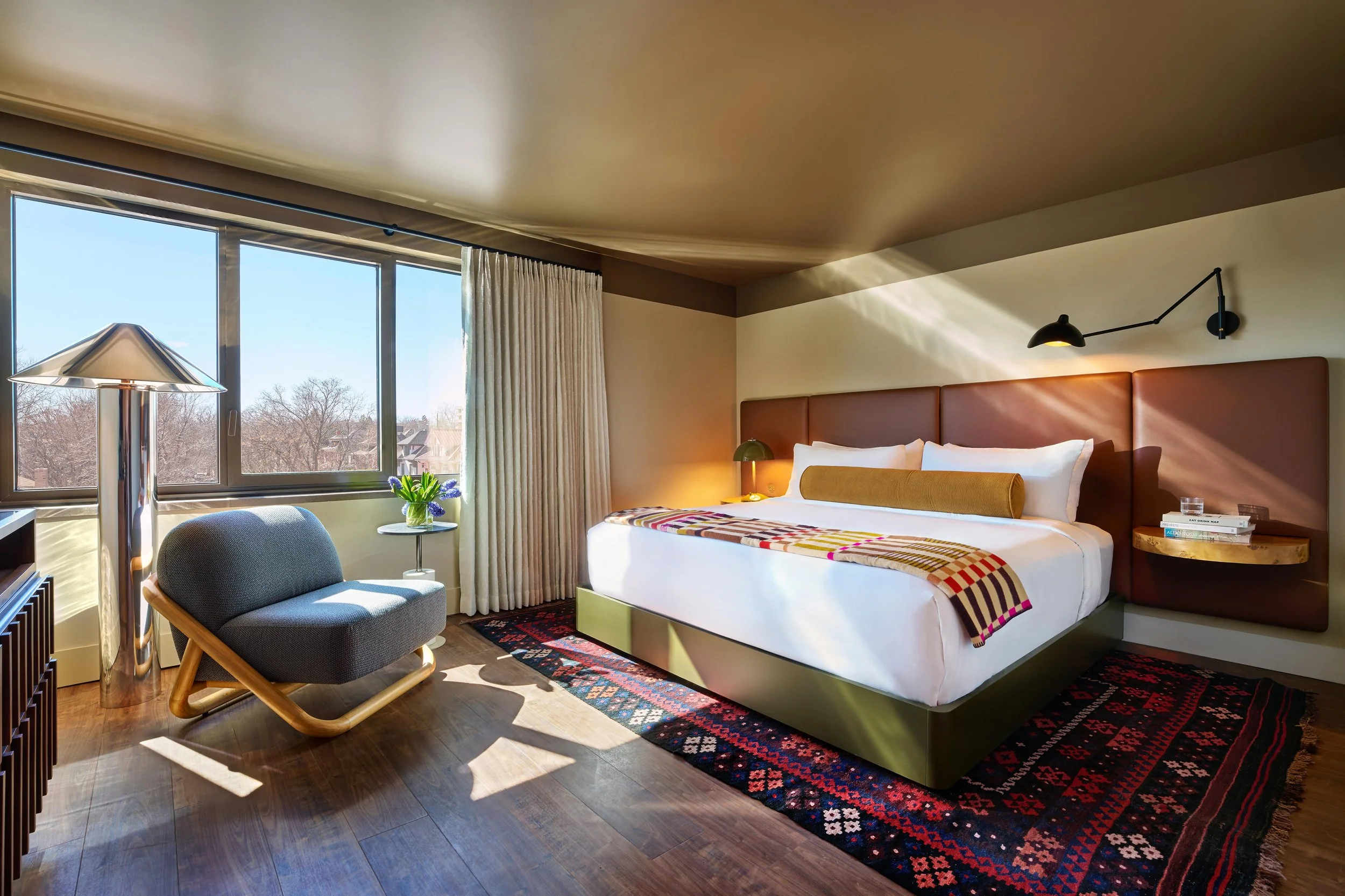 Guest room at the All Inn Hotel in Denver, Colorado, designed by Maximalist, featuring mid-century modern interiors, custom furnishings, warm wood, leather, and layered textiles.