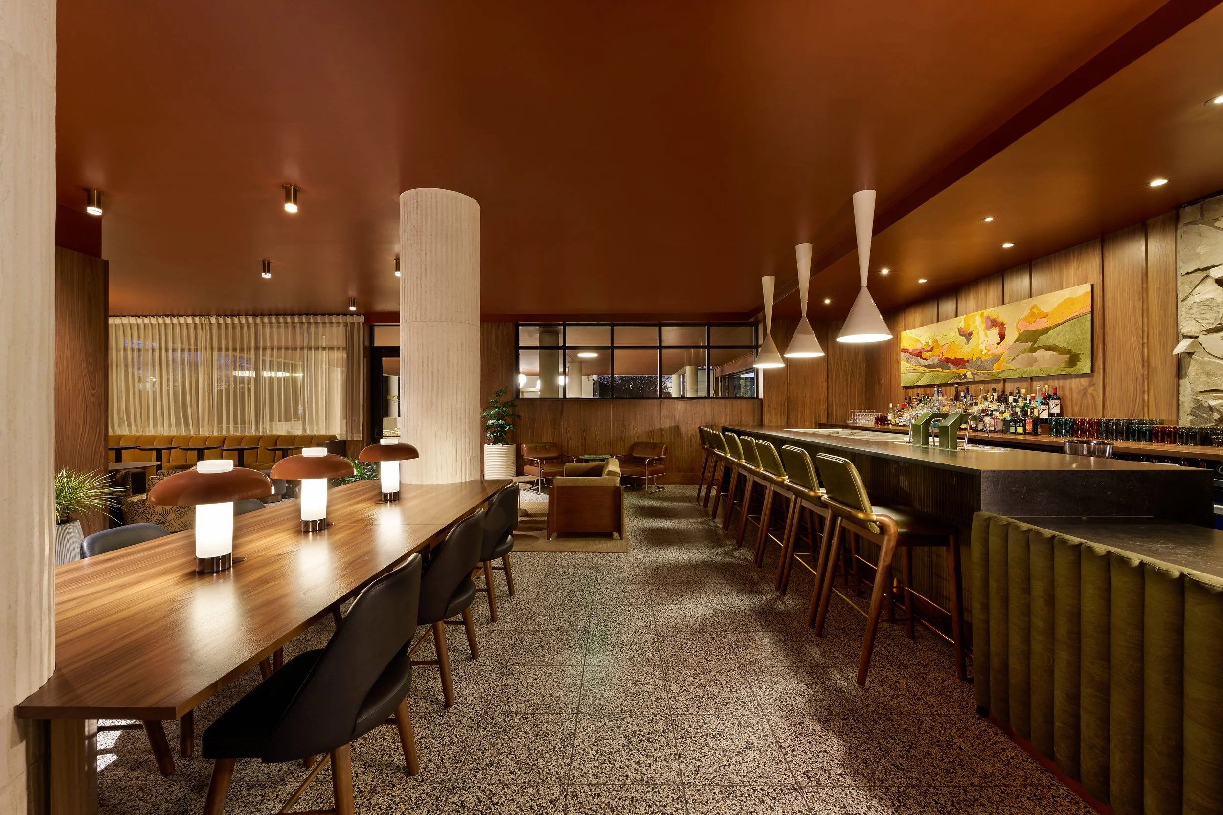 All Is Well lobby and bar at the All Inn Hotel in Denver, Colorado, designed by Maximalist, featuring walnut paneling, terrazzo floors, sculptural lighting, vintage-inspired furnishings, and mid-century modern hospitality design.