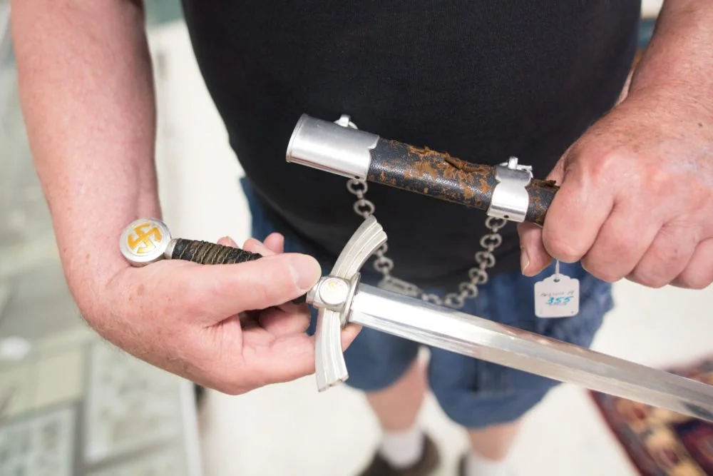 Avid collector and former Vietnam veteran Tom Coulter holds a Nazi military dress dagger that was up for auction. Coulter explained that shiny knives and swords were meant for dress only as reflections could draw the eyes of enemies in battle .