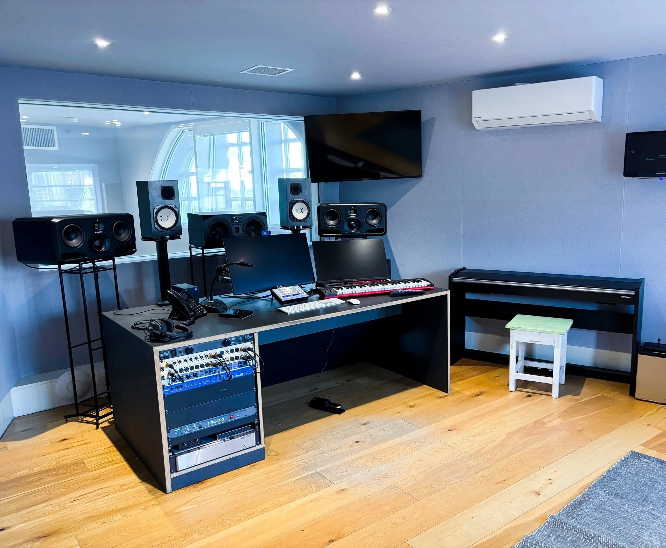  London production studio control room with window to a live room. The loudspeakers are ADAM A77Xs and Yamaha NS-10s.  