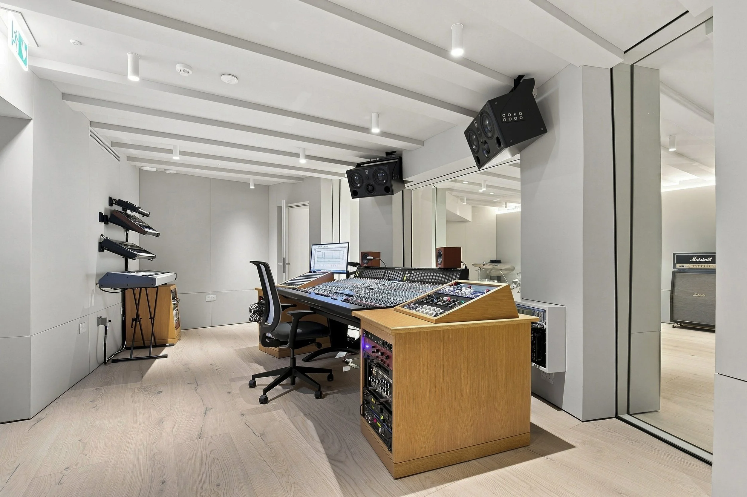  Yellow Technology designed recording studio with synths, ATC speakers, SSL mixing desk and custom rack furniture. Secondary glazed windows to a live room are angled.  