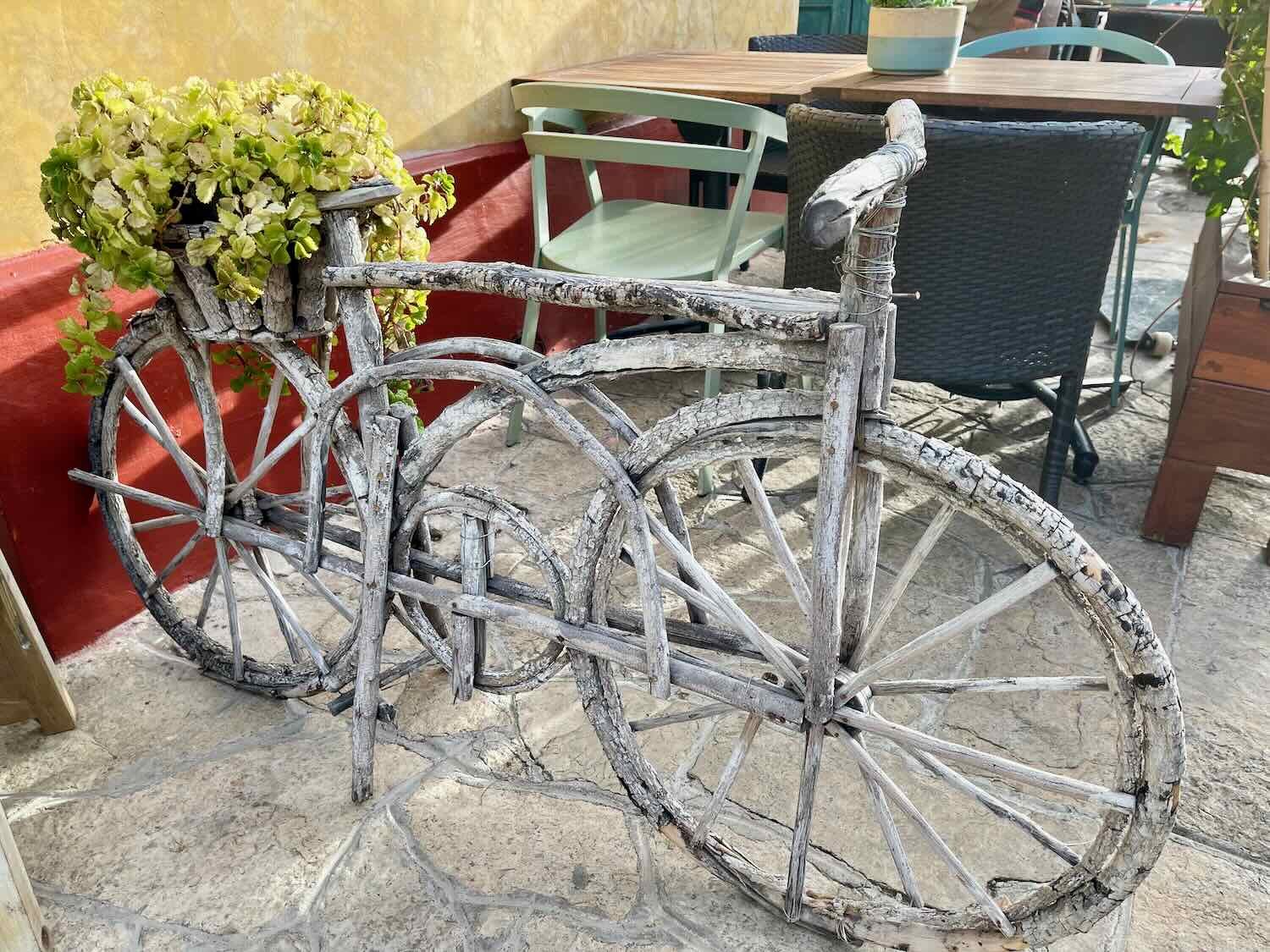 A wooden bicycle on display at an outdoor cafe