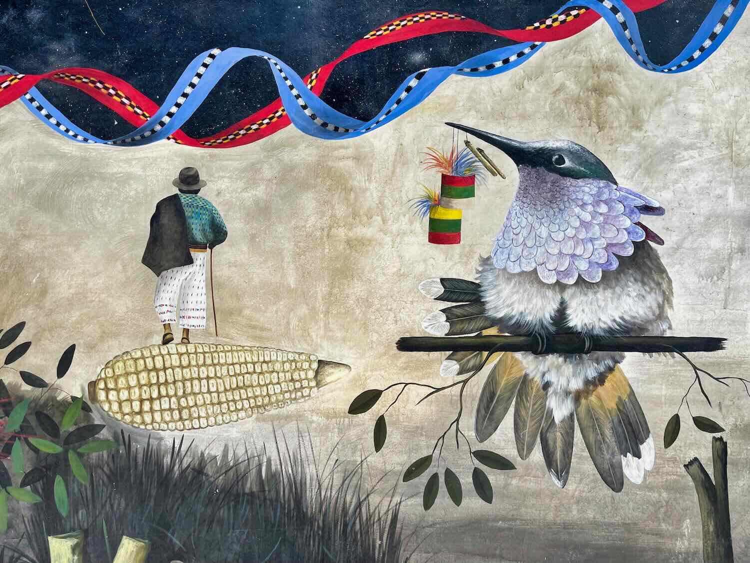Corn provides the path, while a hummingbird holds a 'ronron' (a traditional, Guatemalan noise-making toy)