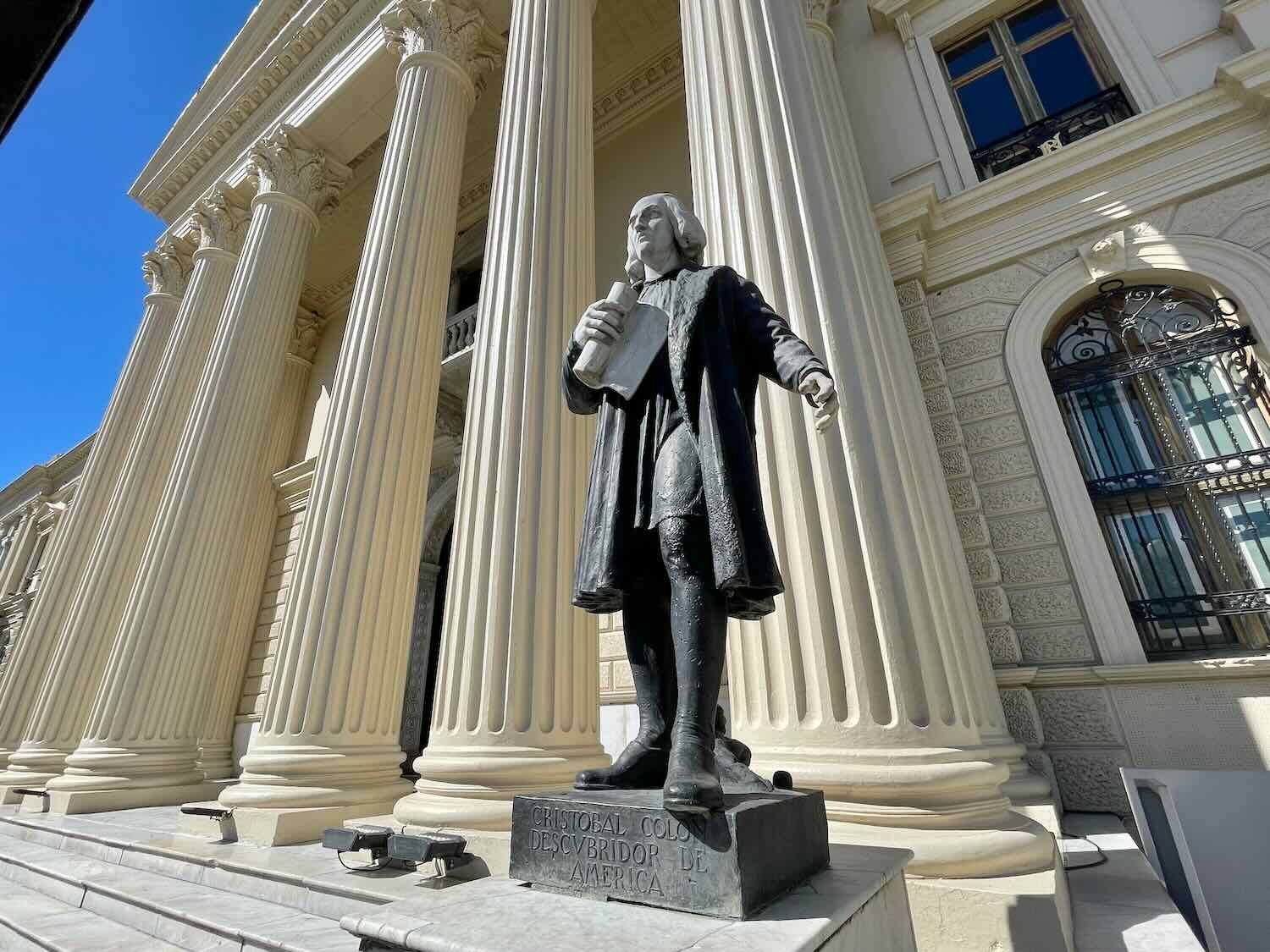 A statue of Christopher Columbus stands on one side of the entrance to the National Palace