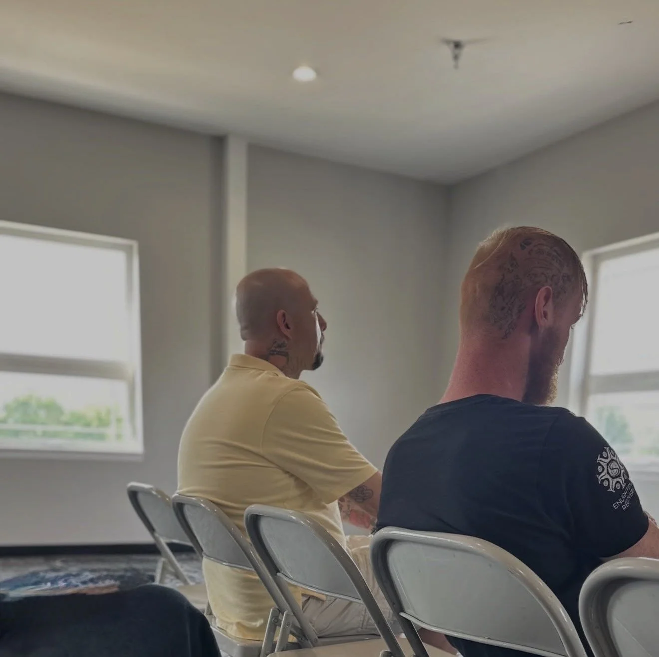 A man in a yellow shirt sitting in a saved and sober recovery group.