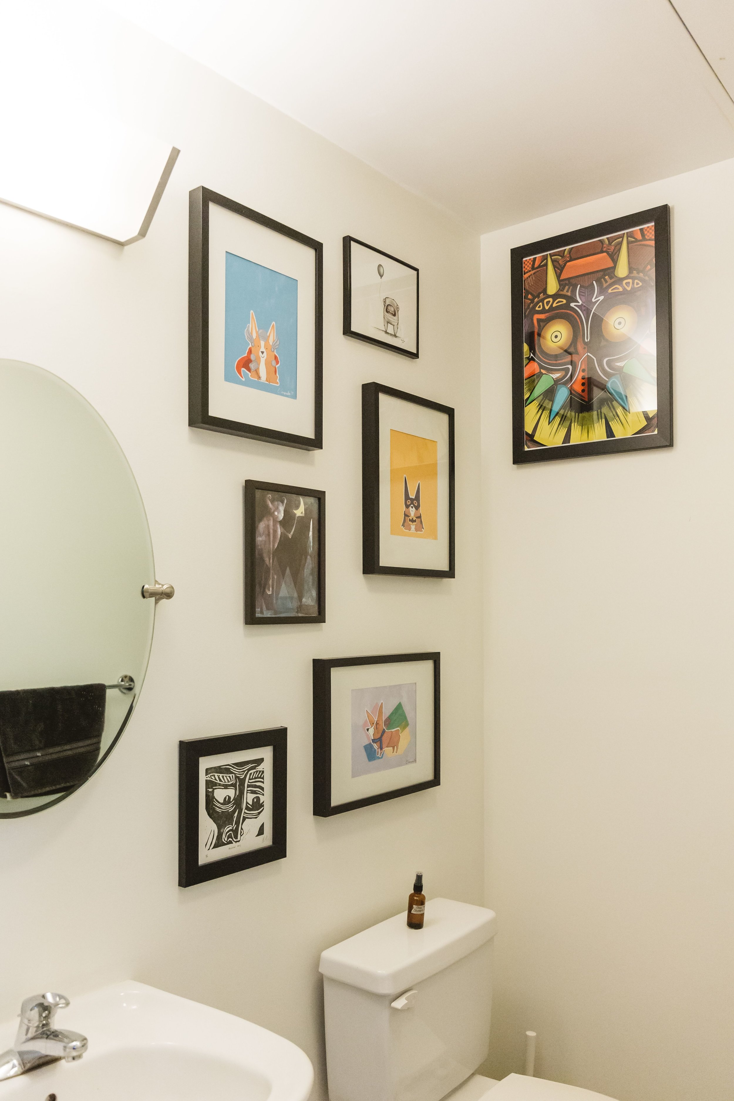 Black frames stand out against the white walls in the bathroom, and add a fun and colorful twist on bathroom decor.