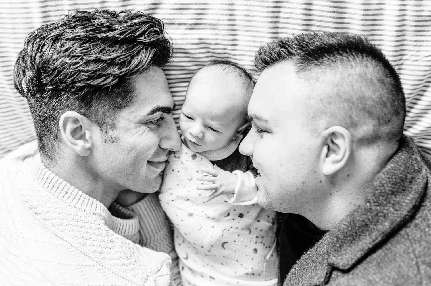 LGBT tow dads snuggling with newborn baby at photoshoot
