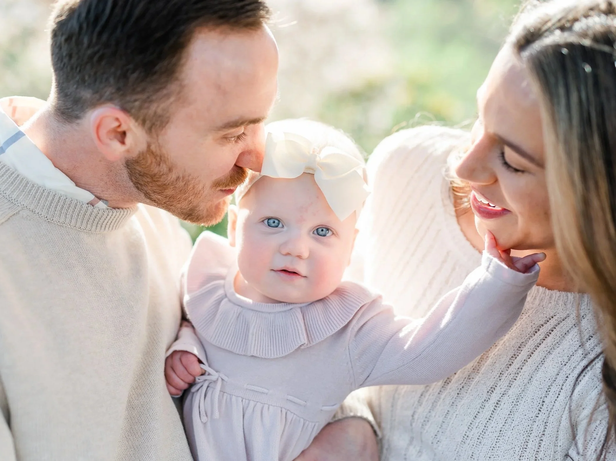 Mom and dad snuggle with baby at Portland Cherry Blossoms