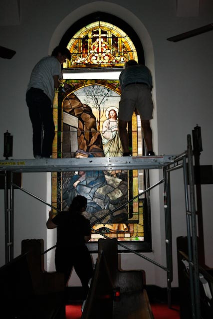 FINAL STEP Rob, Michael, and Heather lift a restored window back into its frame.