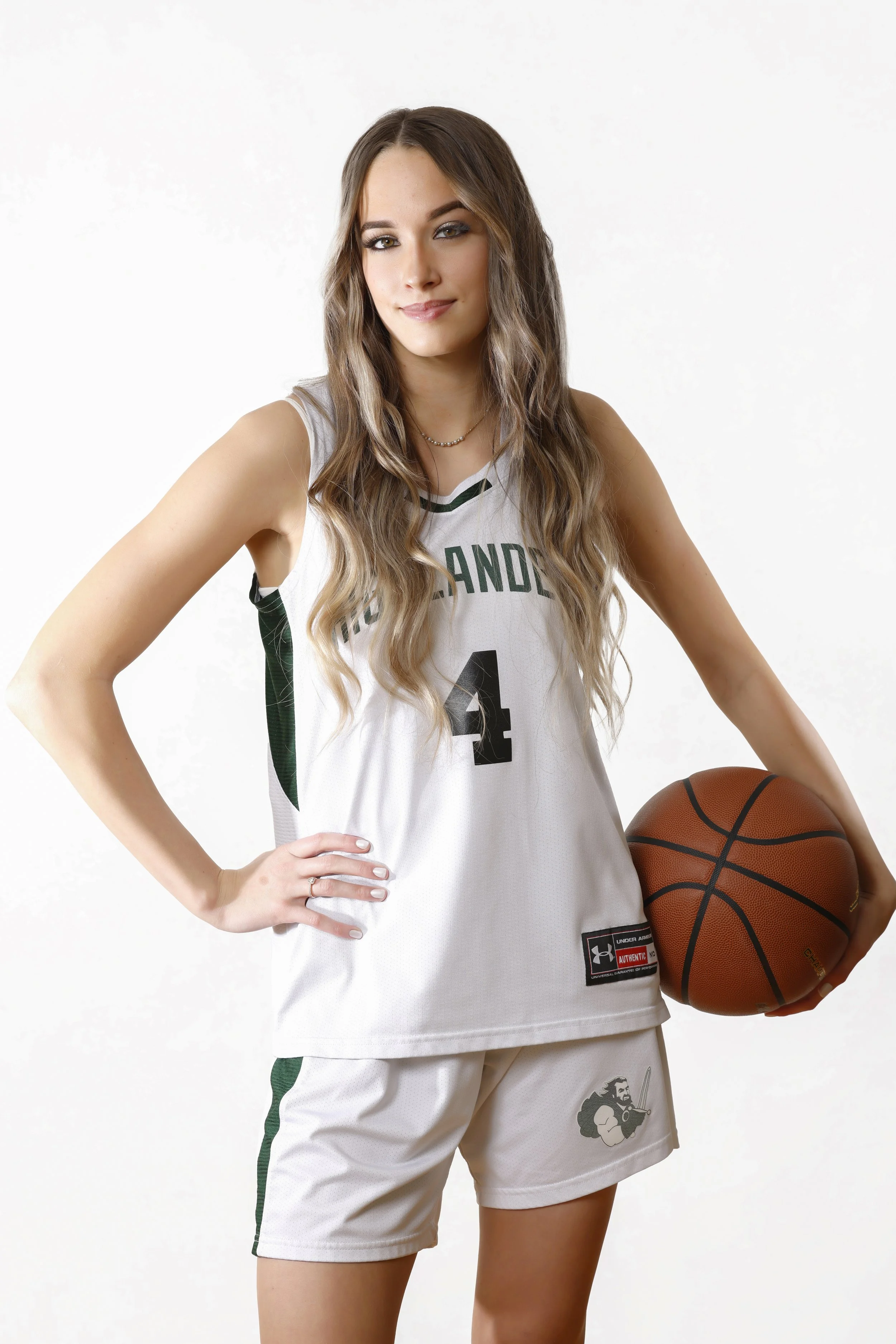 A young woman in a white and green basketball uniform holding a basketball against a white background.