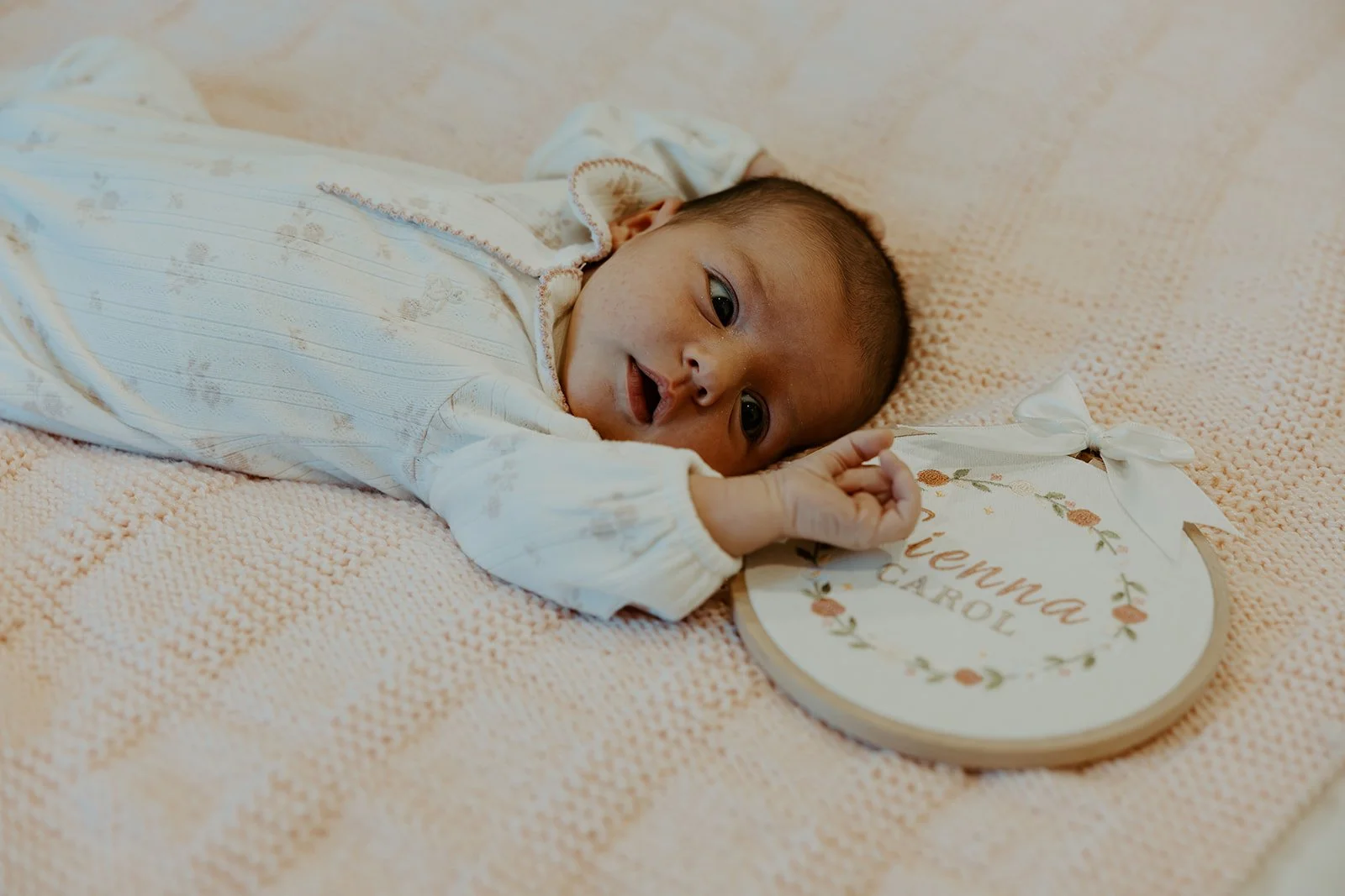 A baby during newborn photos with an embroidered prop