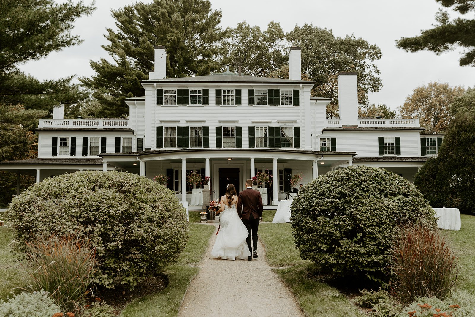 A couple walking hand in hand towards their estate wedding venue