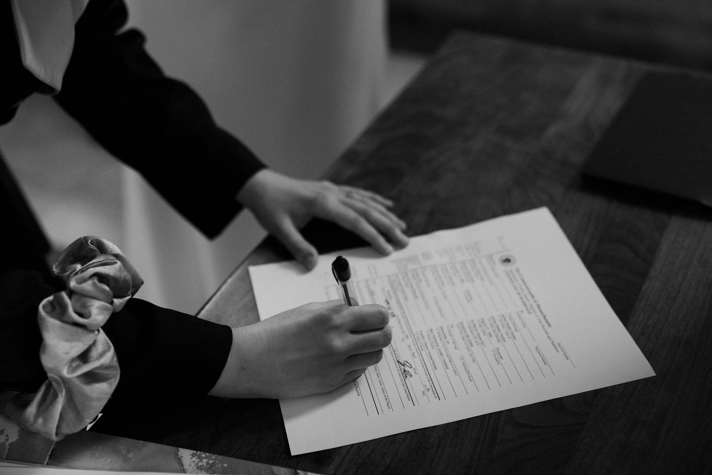 A black and white photo from a Boston elopement of the marriage license being signed