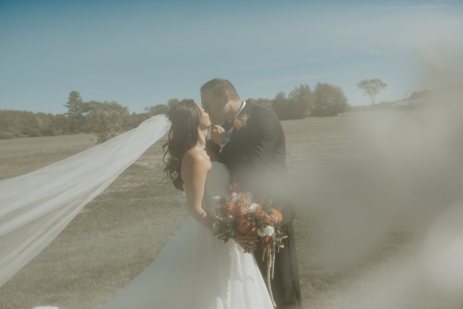 A bride and groom taking veil wedding pictures at their backyard wedding