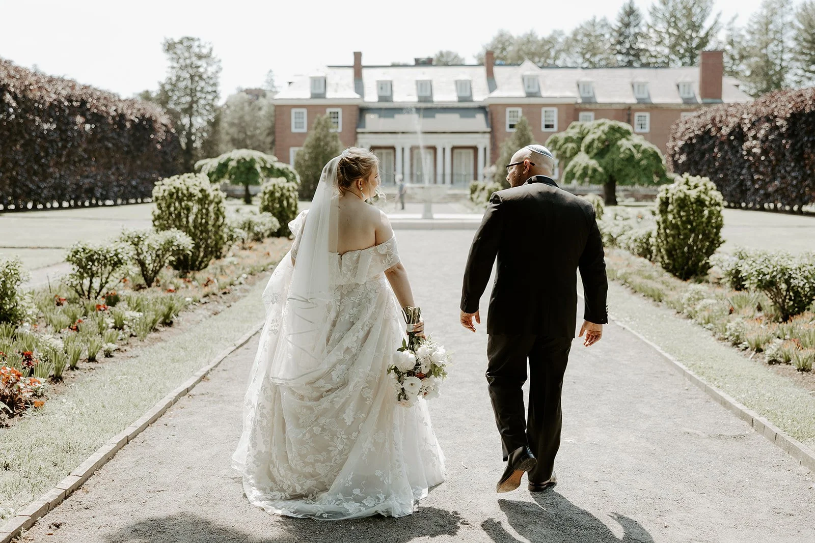 A bride and groom walking towards their estate wedding venue
