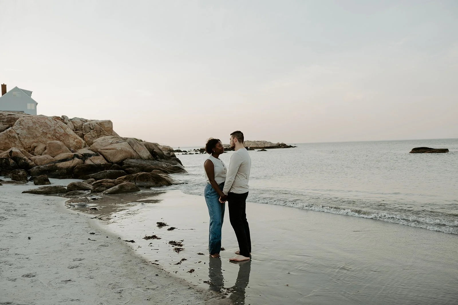 A couple standing on the beach holding hands during beach engagement photos