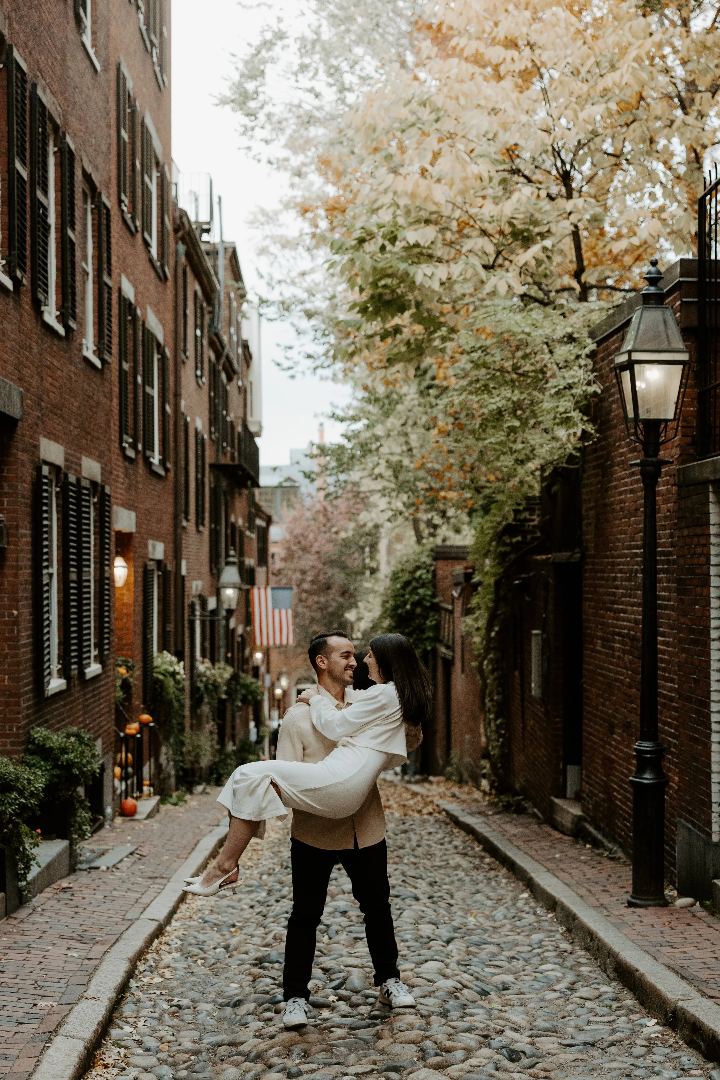 A couple posing on cobblestone streets for their engagement photoshoot, captured by a Boston engagement photographer