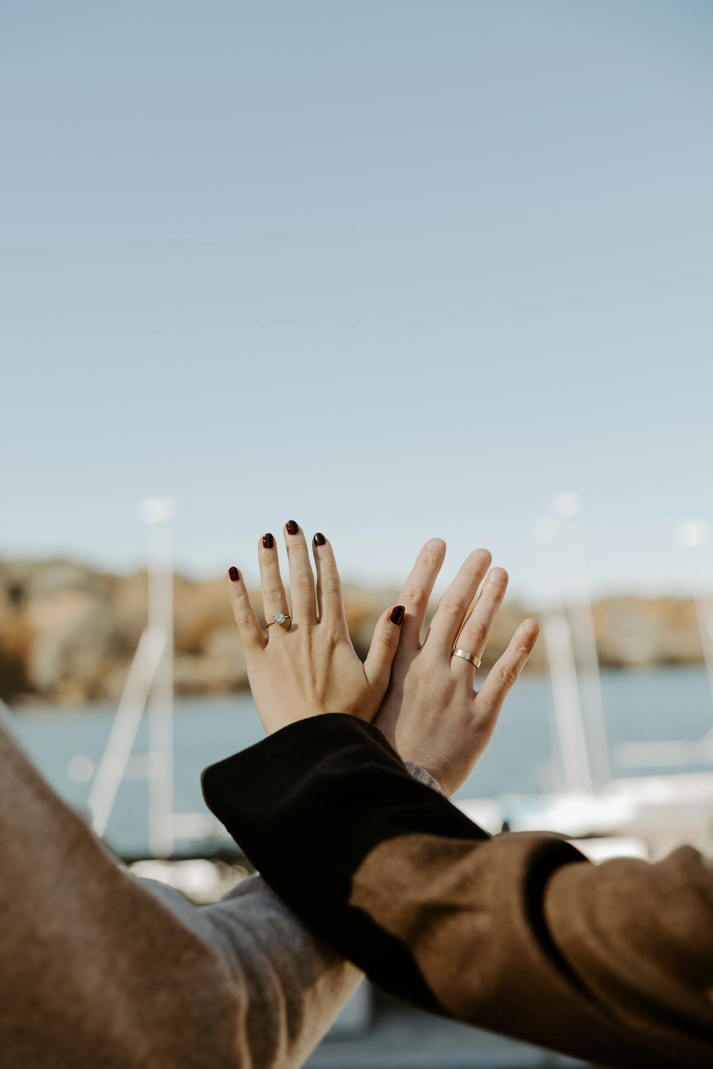 A couple holding out their hands showing off their rings, captured by a Boston engagement photographer