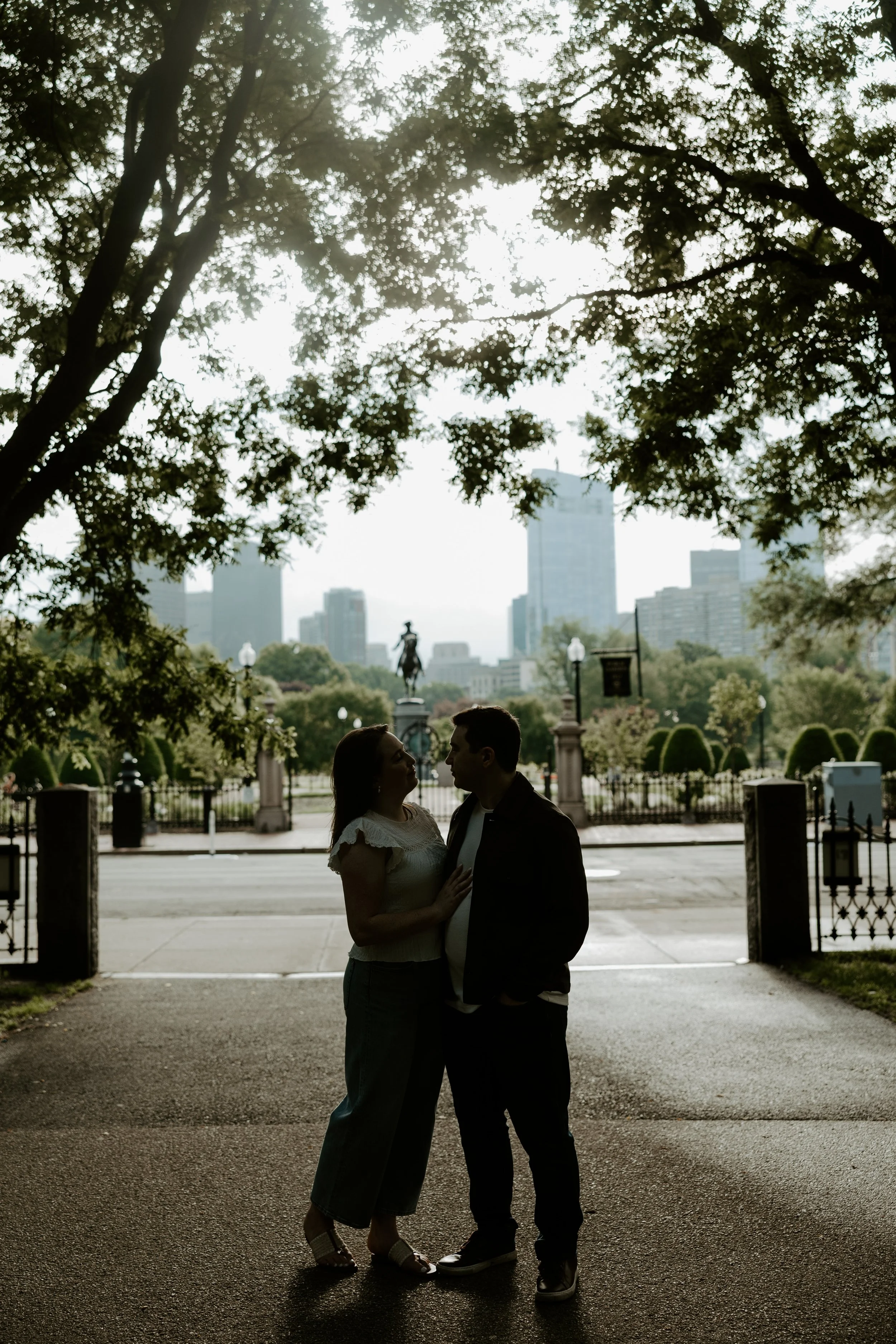 A couple posing with the city skyline behind them, captured by a Boston engagement photographer