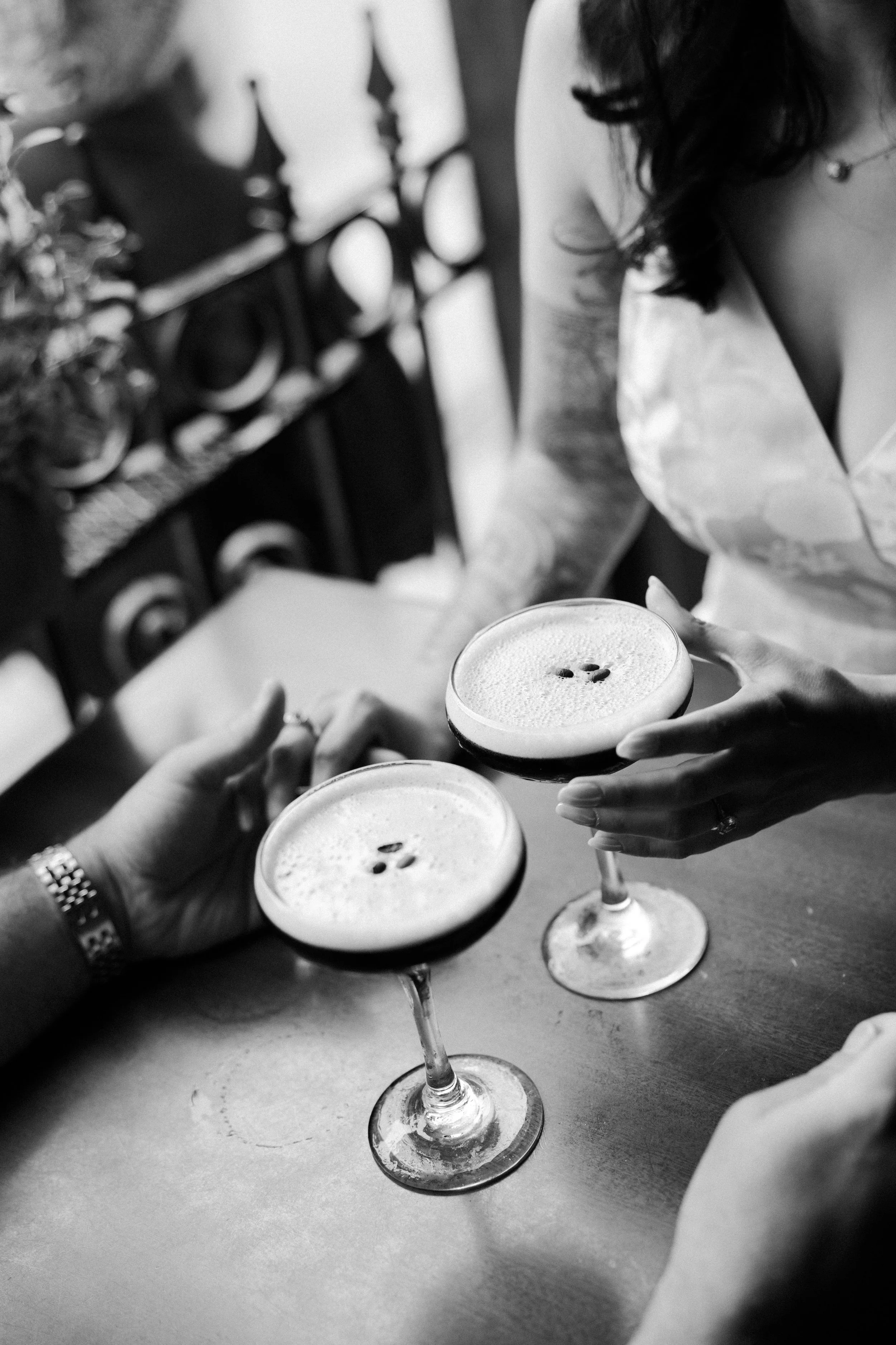 A black and white photo of a couple having espresso martinis during their engagement photoshoot